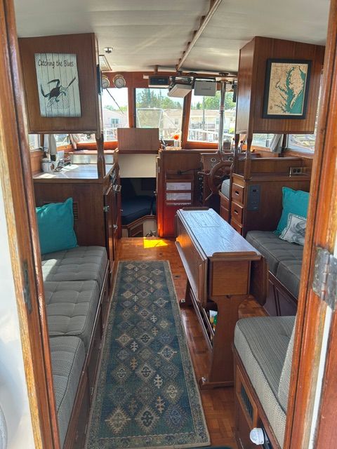 Interior of a 1980 Grand Banks 32 Sedan yacht, featuring wood furnishings and blue cushions.
