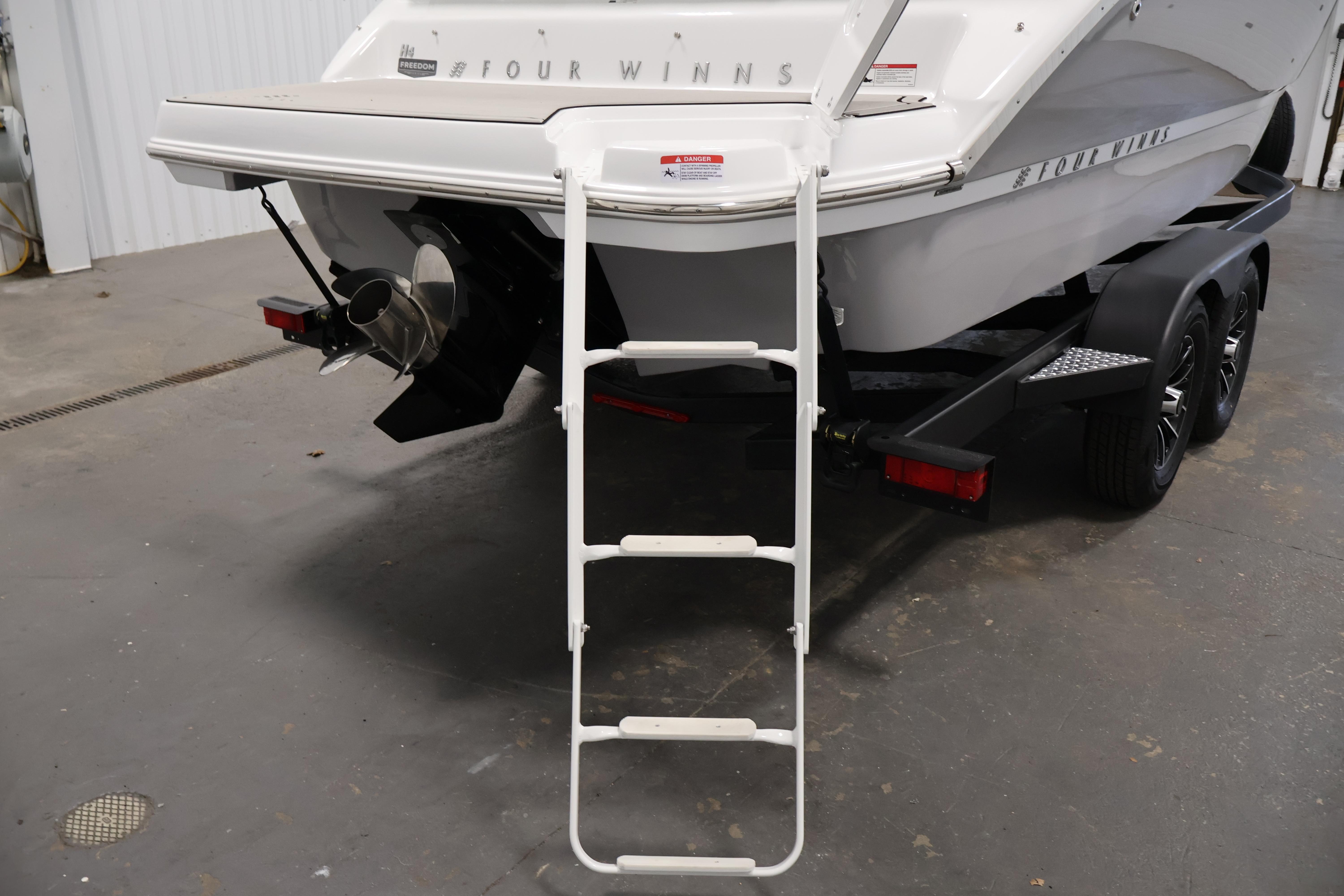 2026 Four Winns H4 Freedom boat with ladder and trailer in a garage.