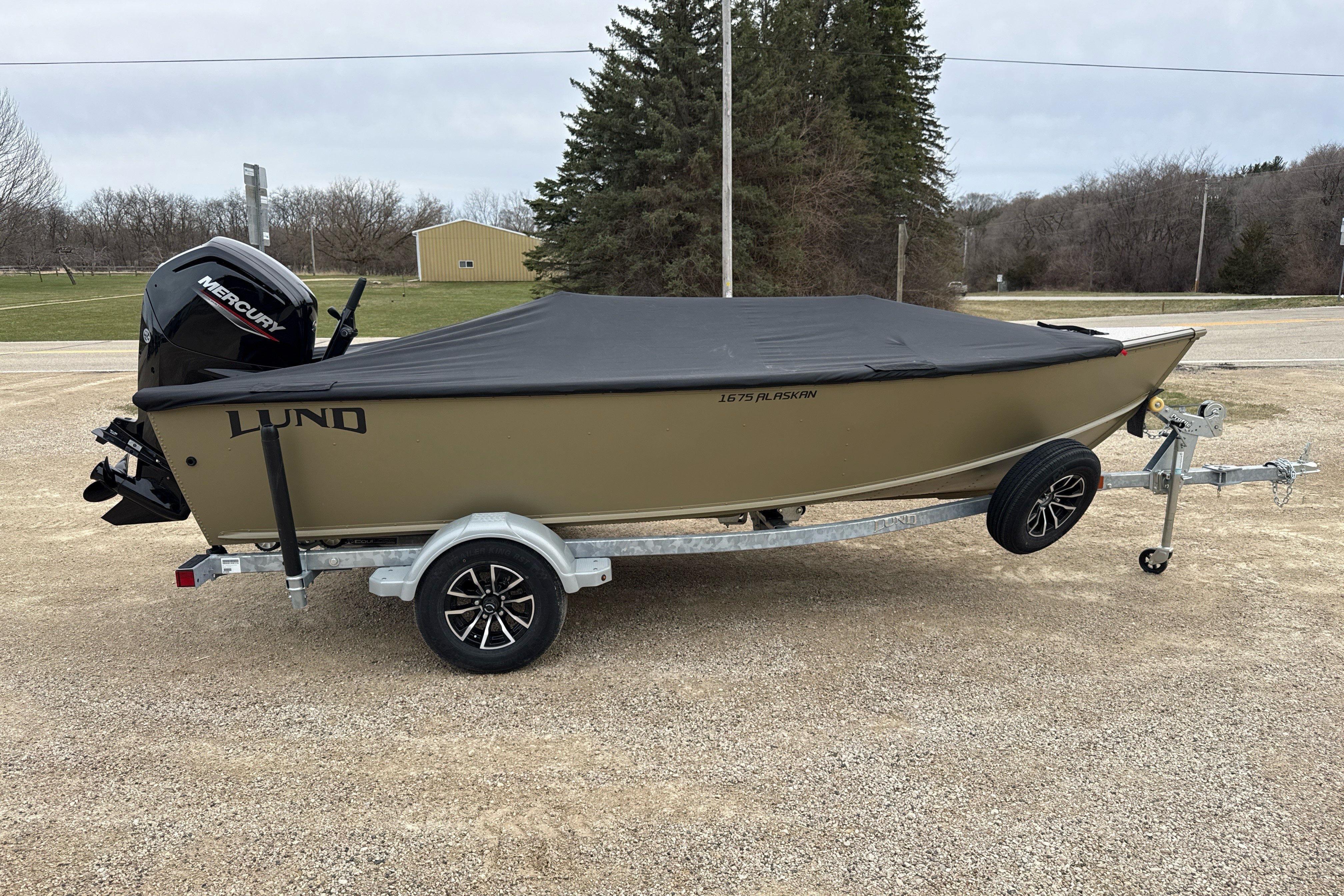 2026 Lund 1675 Alaskan Tiller boat on trailer, covered, with Mercury outboard motor.