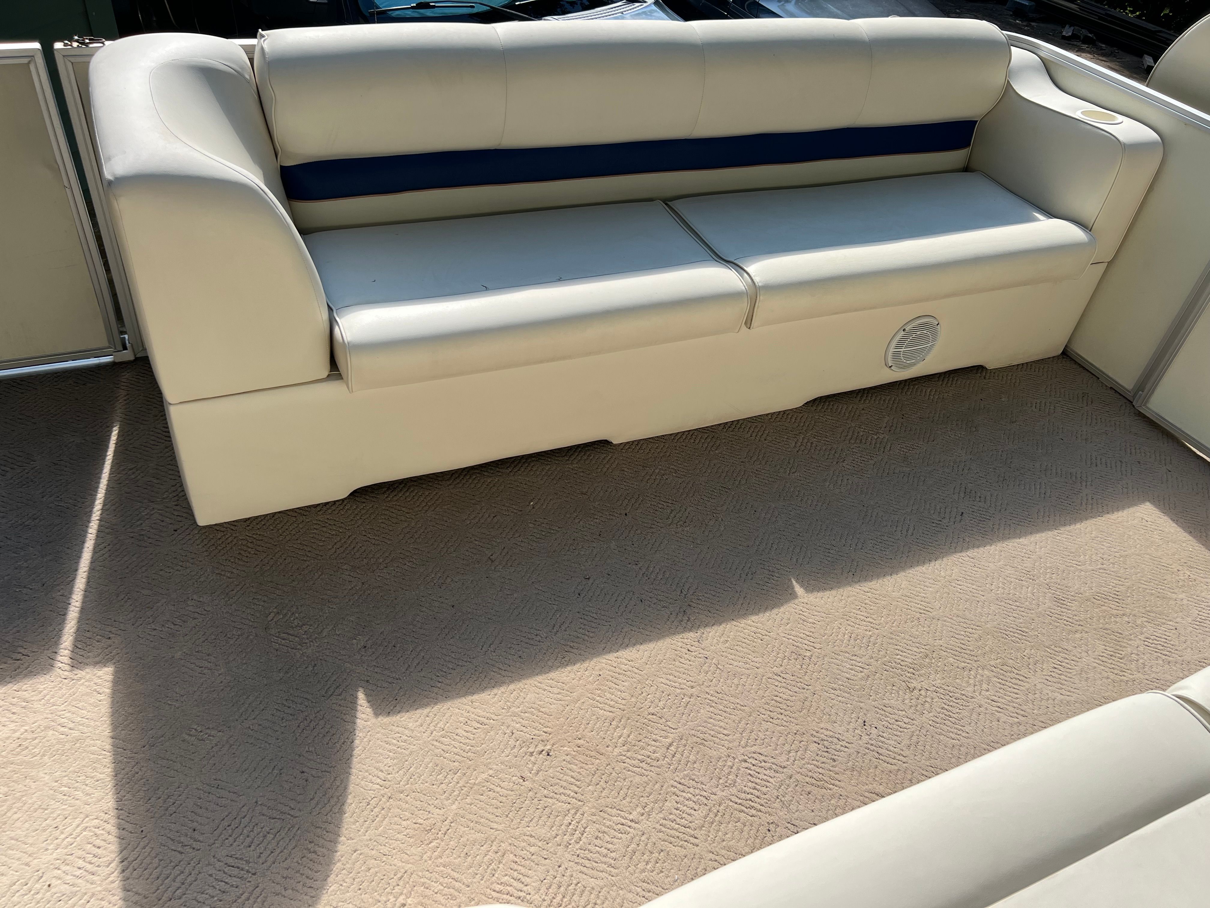 A cream-colored sofa on a boat with a blue trim.