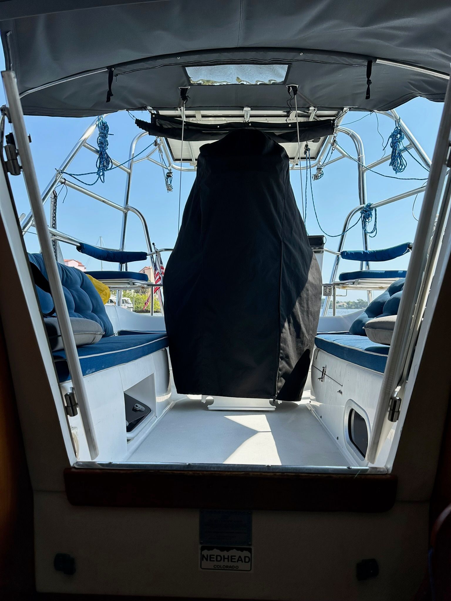 View from inside a boat towards the cockpit with blue seats and ropes.
