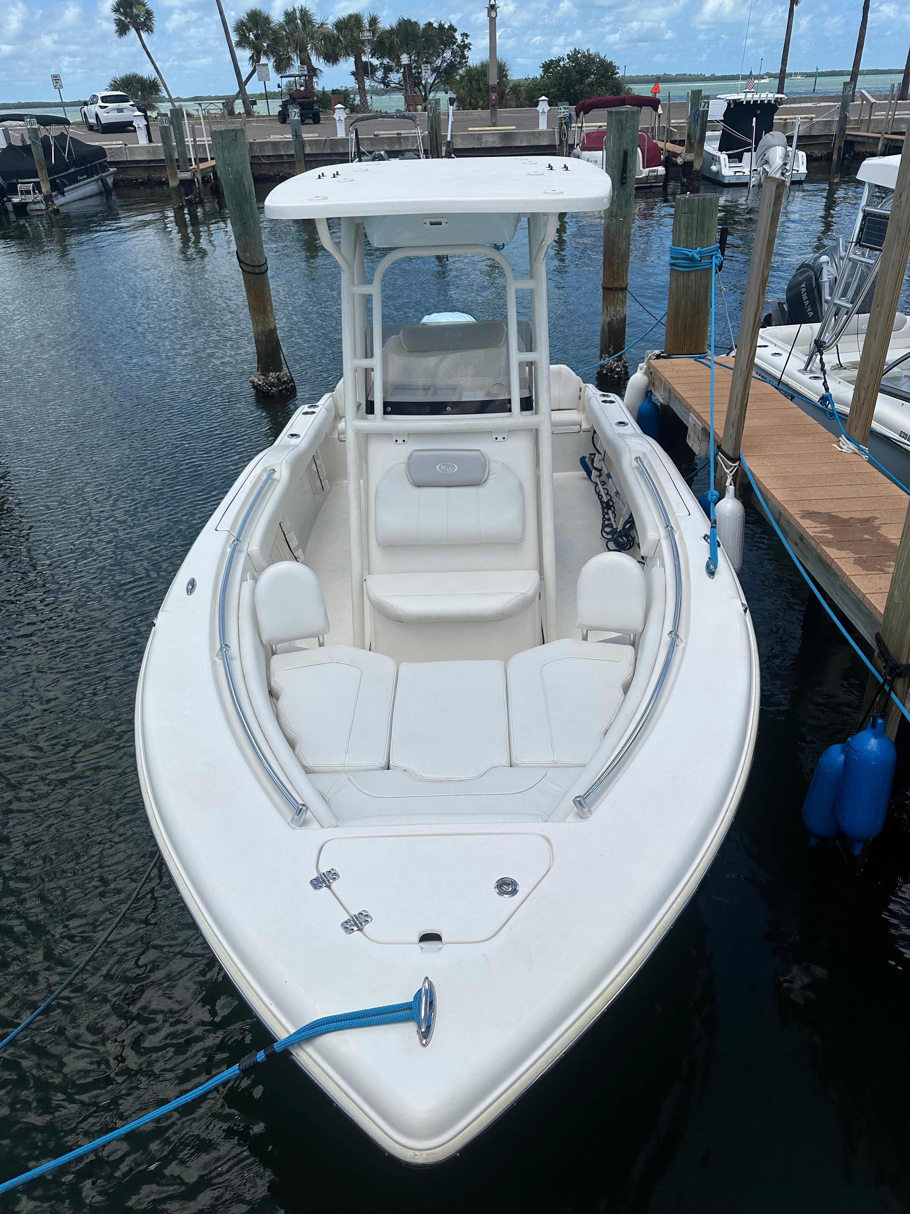 A white boat is docked in a marina, surrounded by other boats and docks.