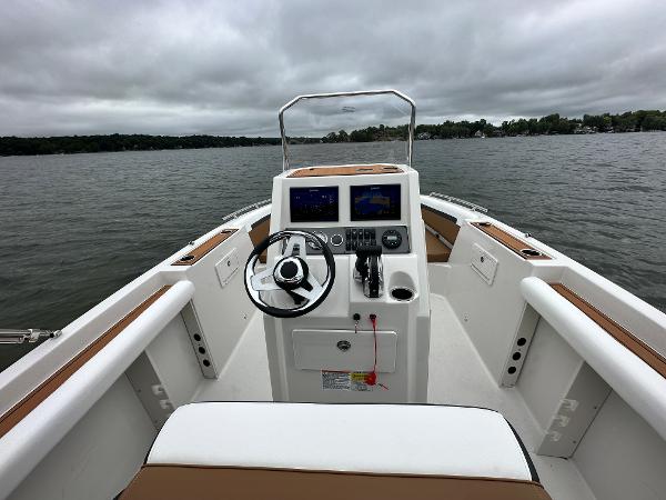 2025 Starcraft SVX 211 OB CC boat interior with steering wheel and control panel on a lake.