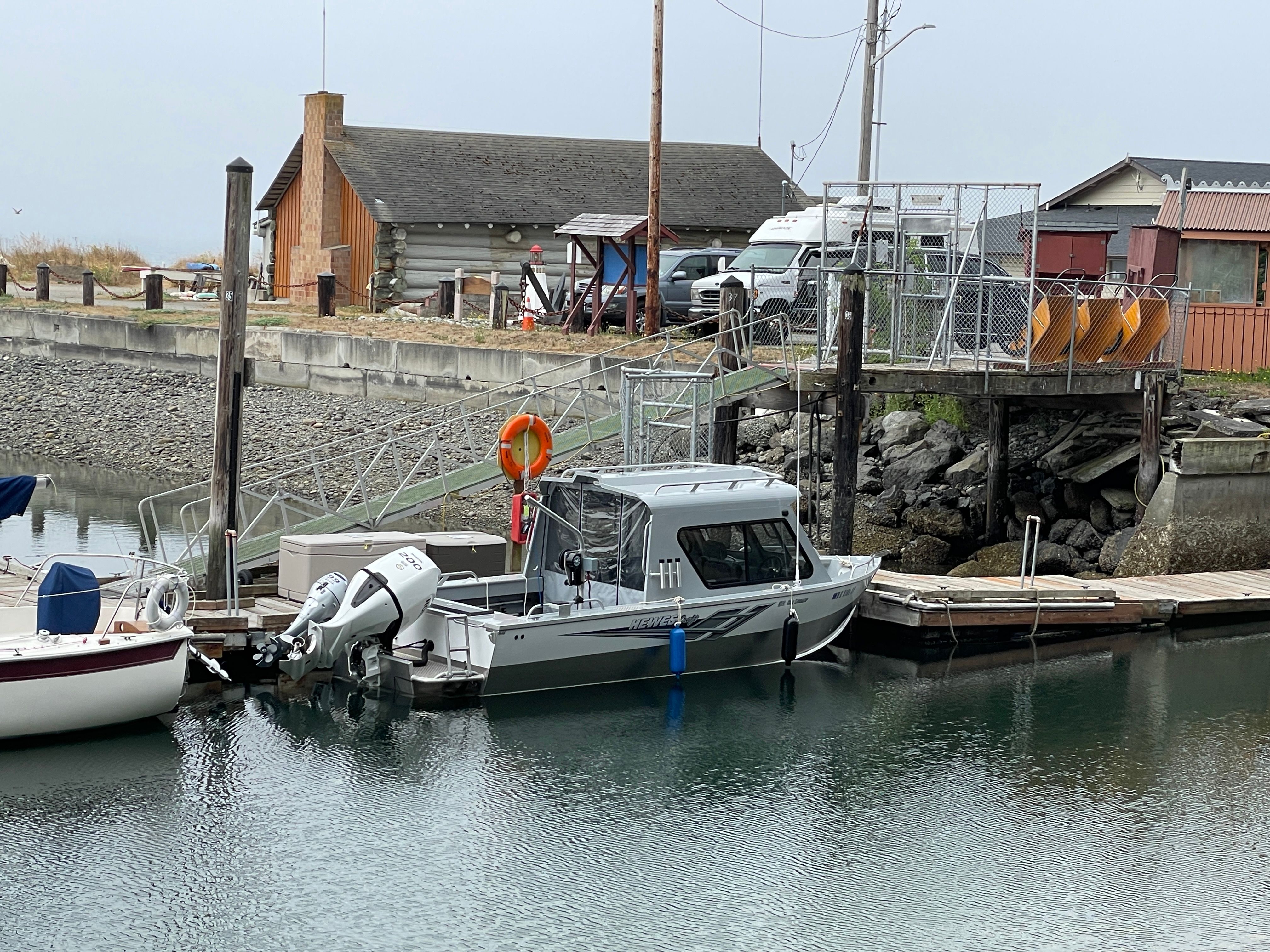 A 2021 Hewescraft 210 Sea Runner ET Hardtop docked in a calm marina.