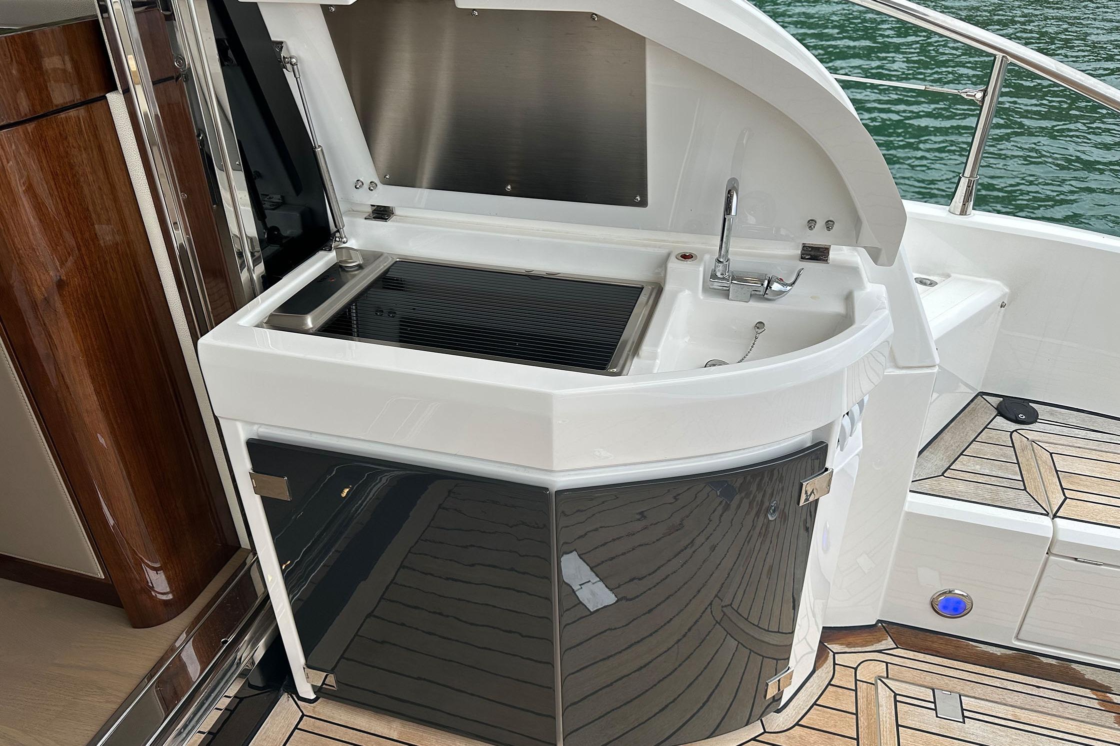 Outdoor kitchenette on 2022 Fairline Targa 50 GT yacht with sink and grill.