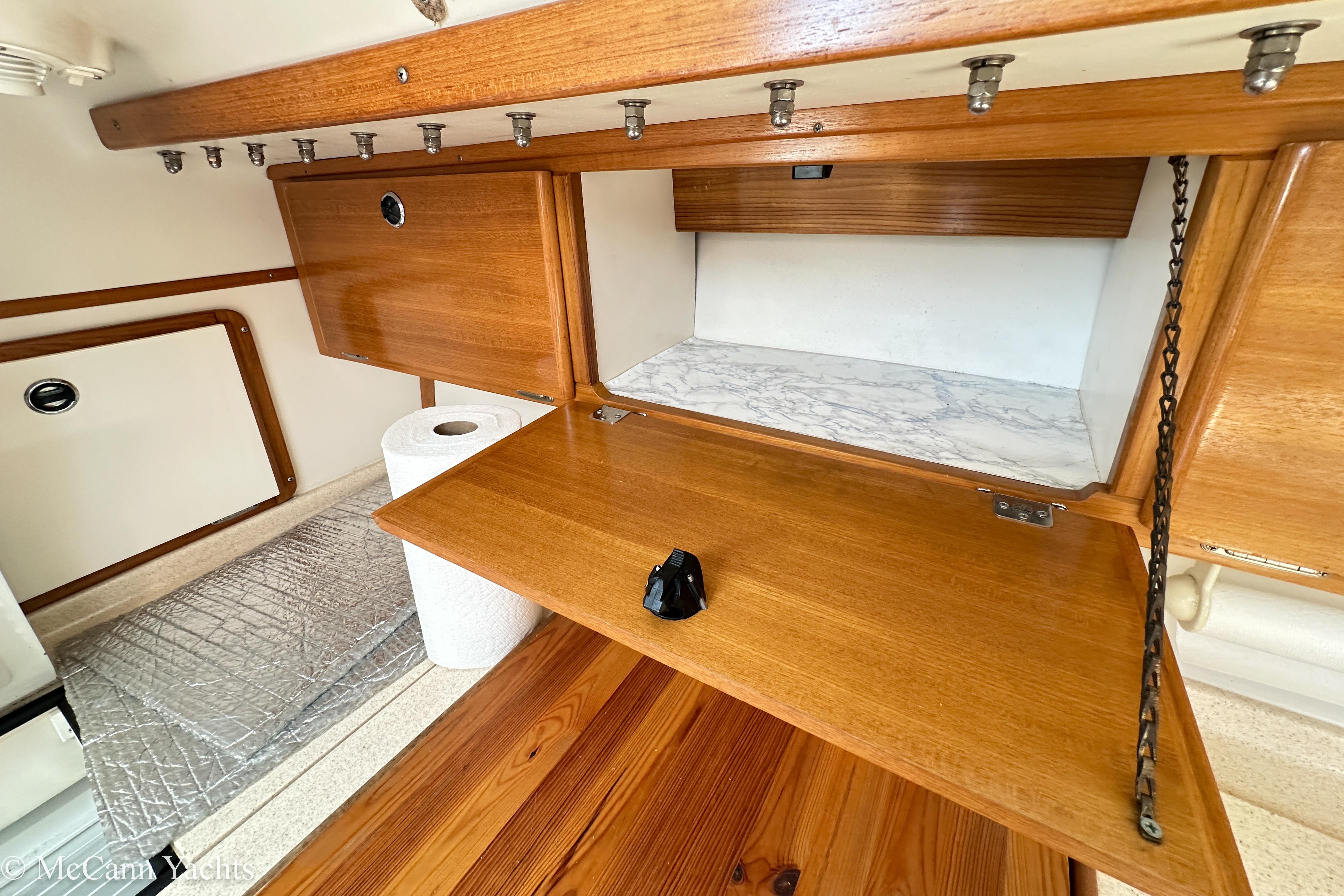 Wooden cabinetry in a 2003 Catalina 320 yacht interior, featuring open storage and paper towel holder.