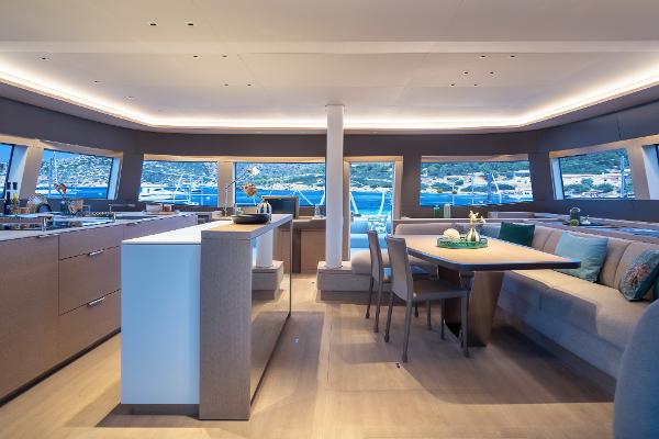 Luxurious interior of 2025 Lagoon SIXTY 5 yacht with modern dining area and panoramic windows.
