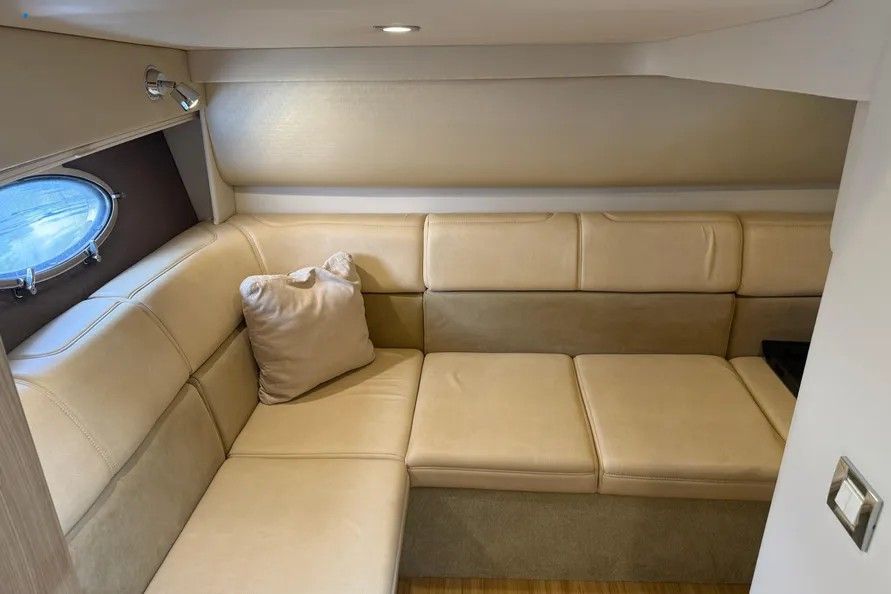 Interior of a 2016 Formula 37 Performance Cruiser with beige leather sofa and porthole.