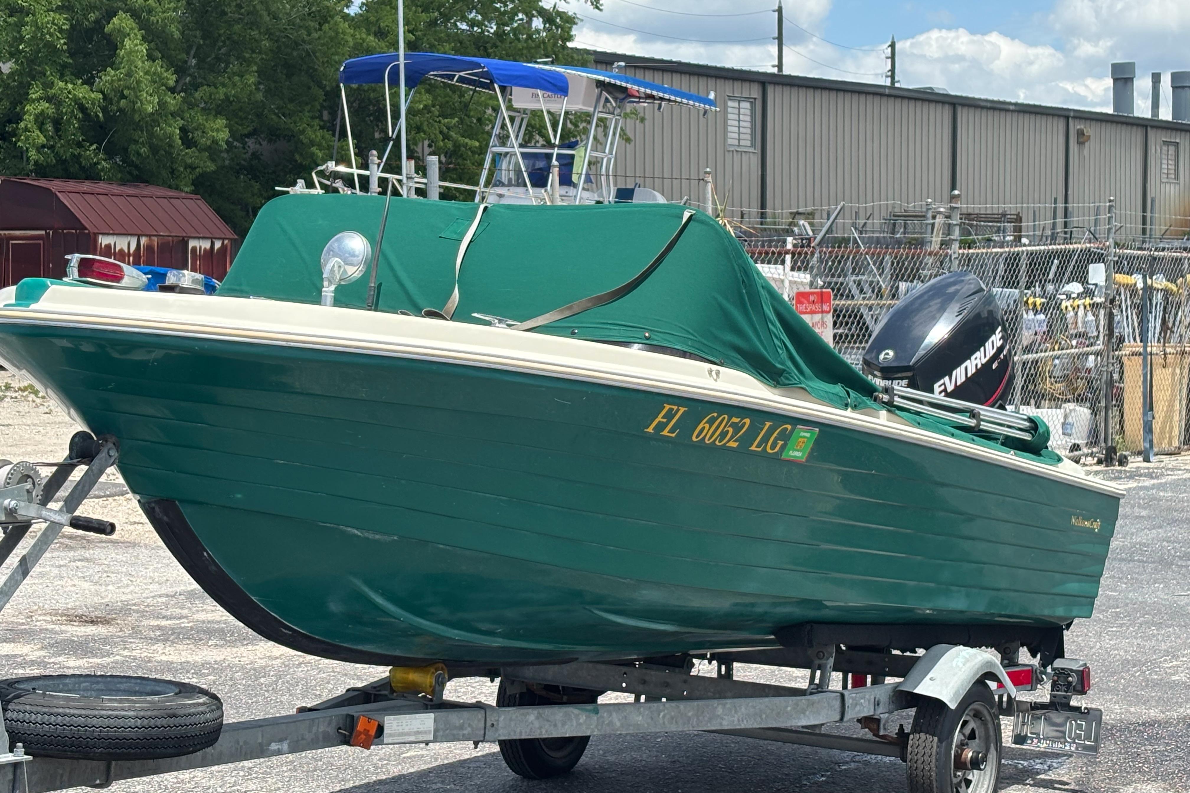 1966 Mohawk 15 boat on trailer with green cover and Evinrude motor.