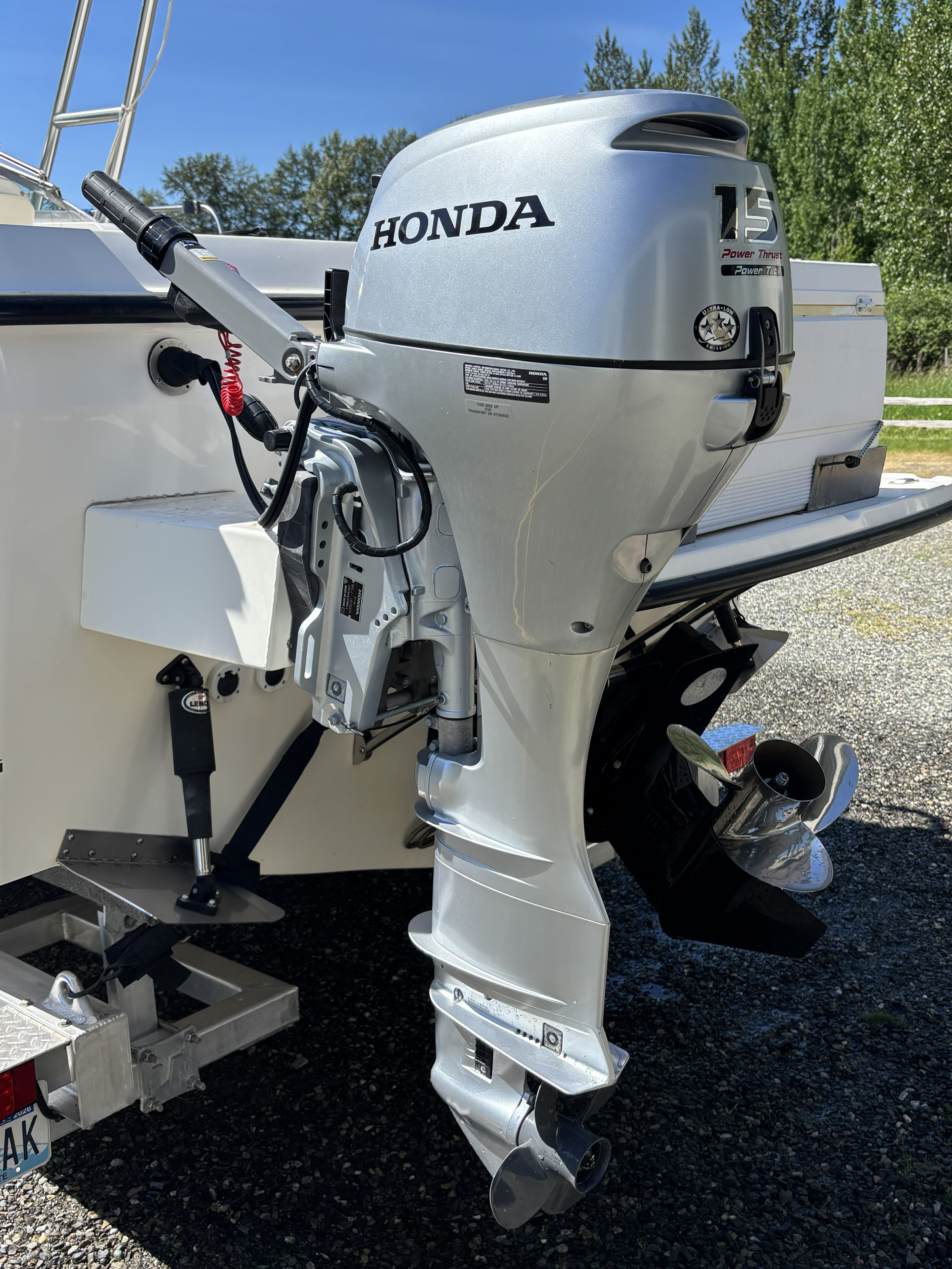 A Honda outboard motor is mounted on the stern of a boat on a trailer.