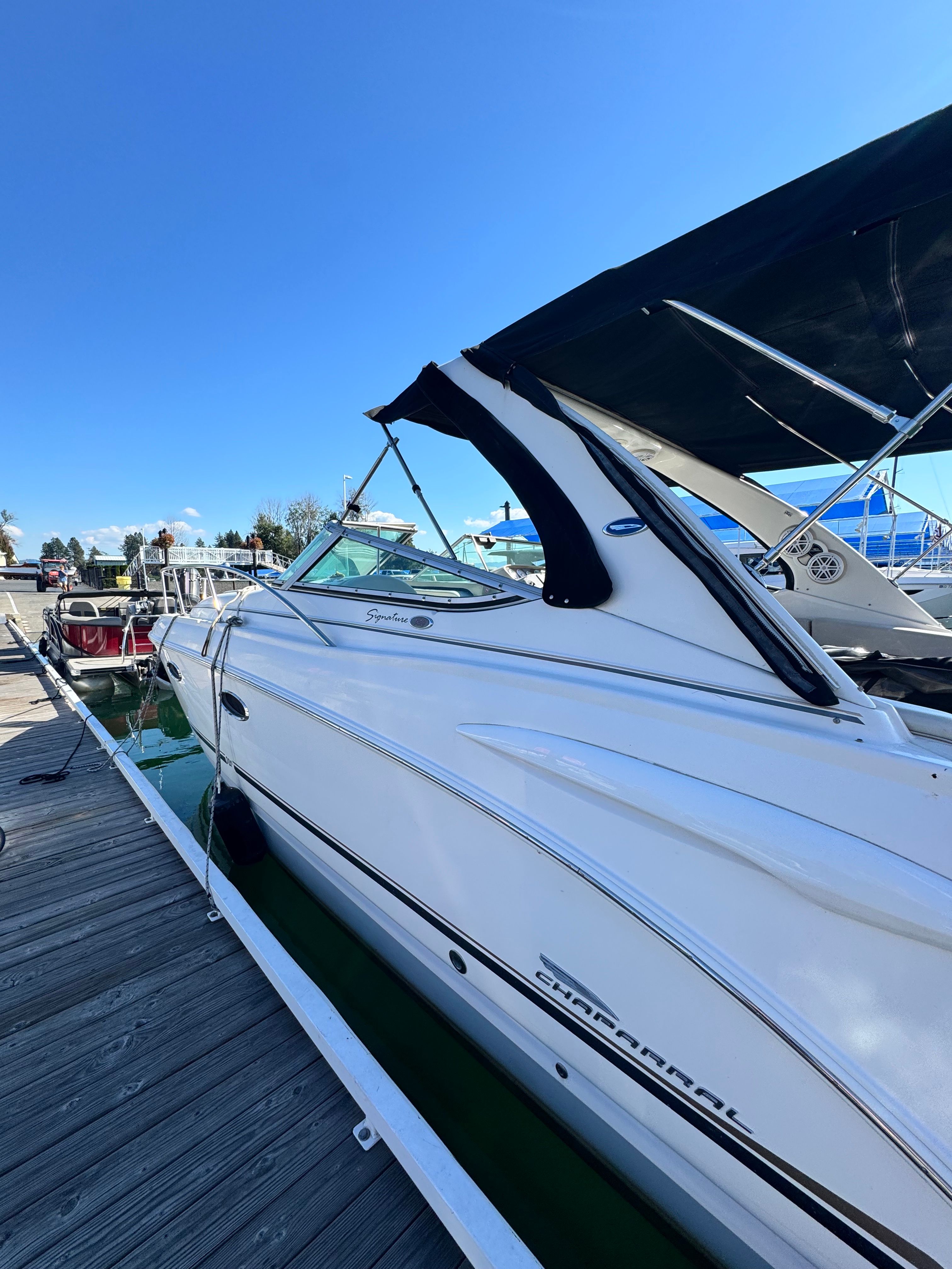 A white 2004 Chaparral Signature 330 boat docked, featuring a black canopy.