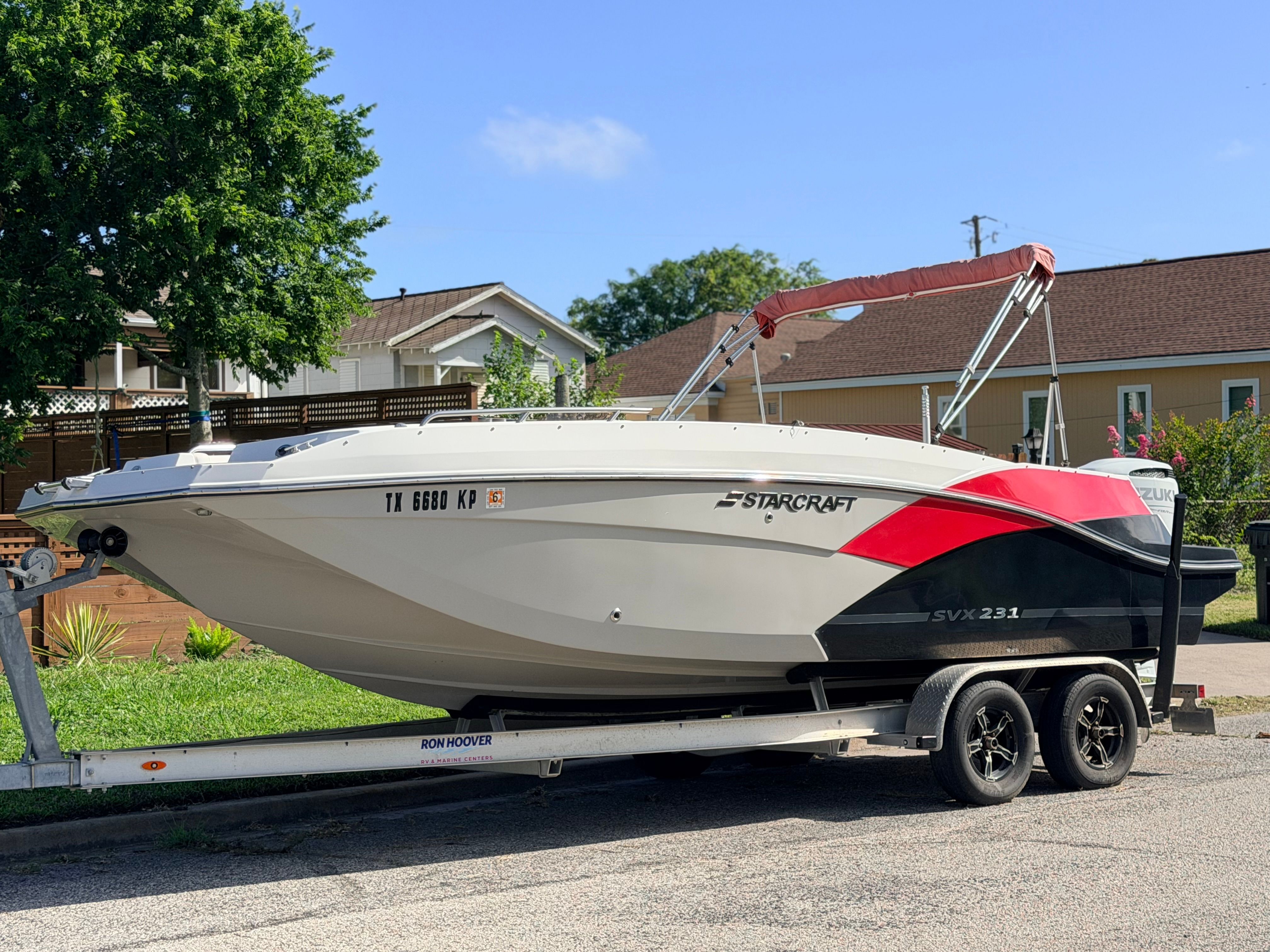 A Starcraft SVX 231 boat on a trailer, parked in a residential area.