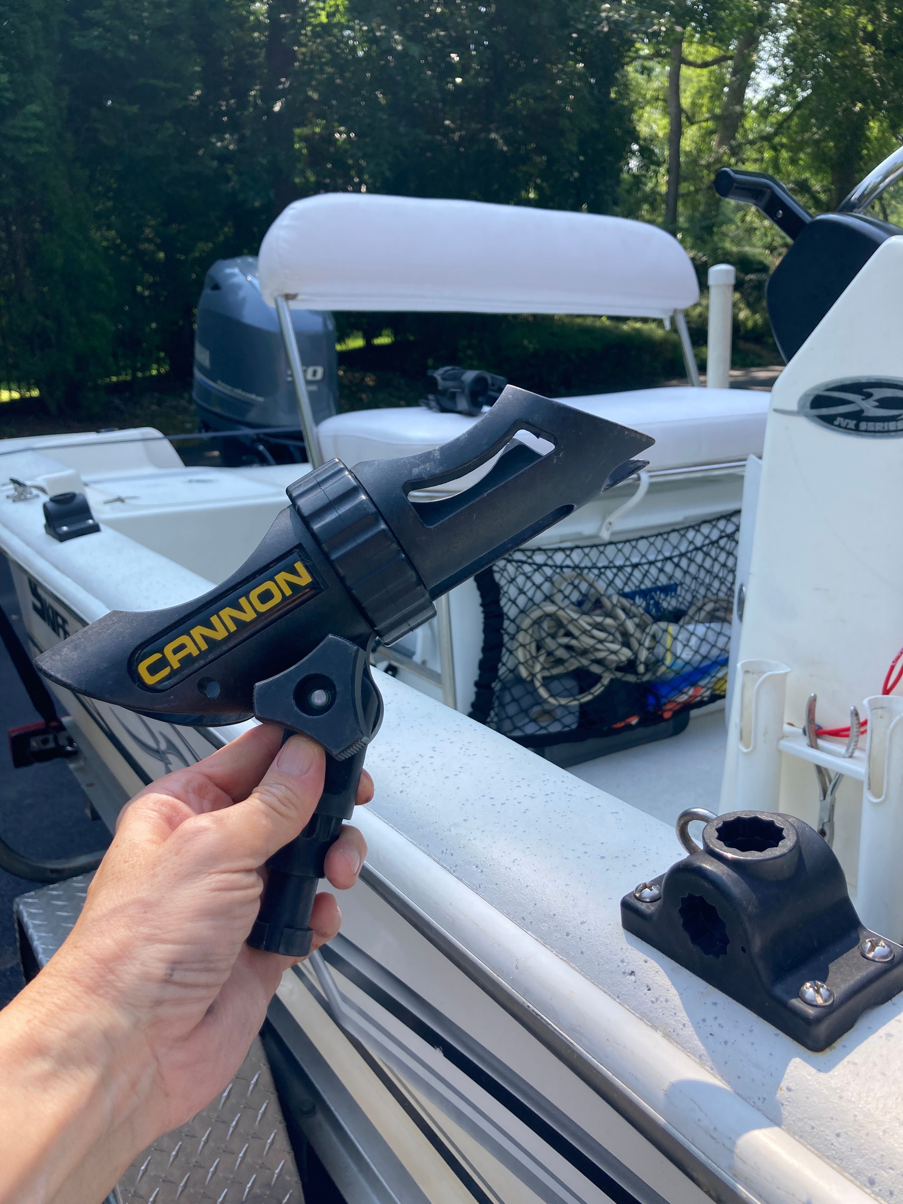 A hand holds a fishing rod holder on a Carolina Skiff JVX16CC boat.