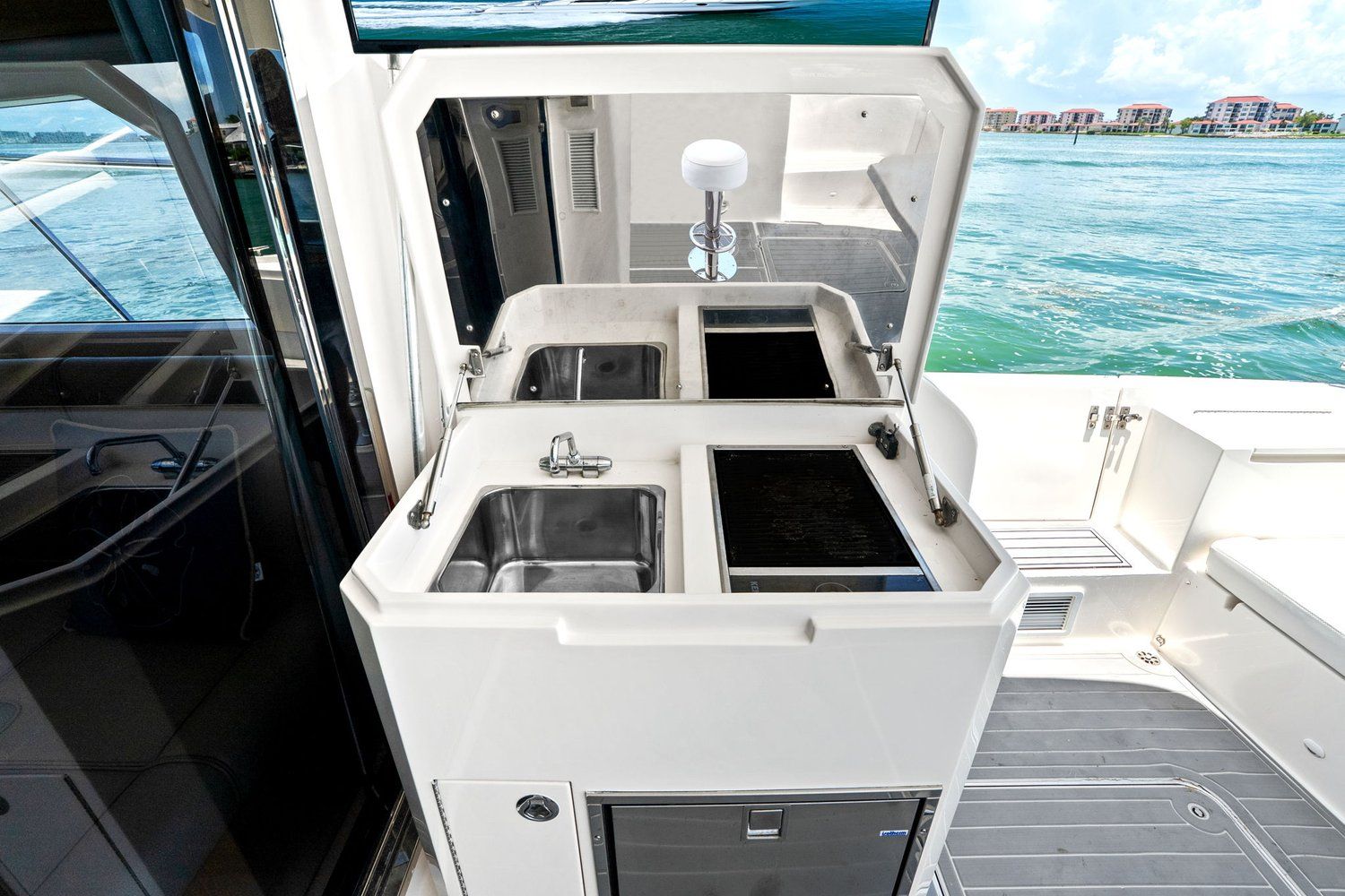 Galley on a catamaran with dual sinks and cooktops, view of water in the background.