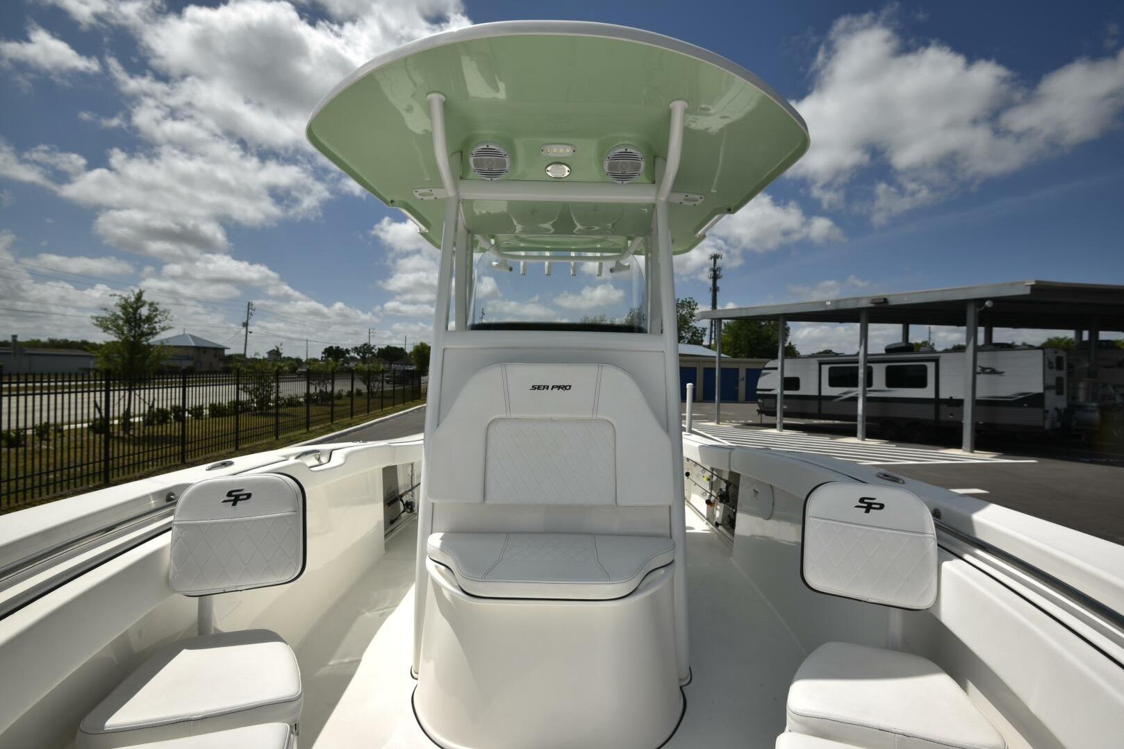 2023 Sea Pro 239 Deep V CC boat interior with seating and console under a blue sky.