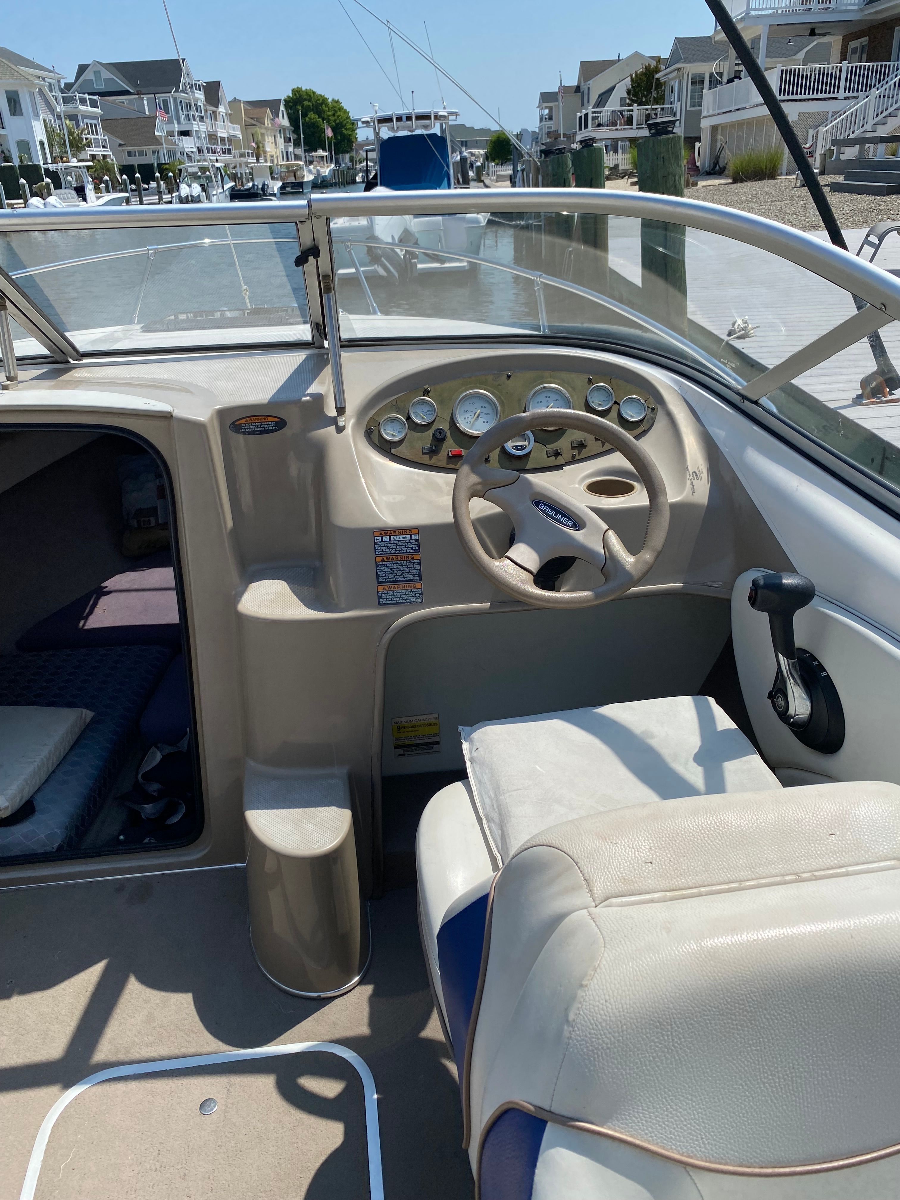 The image shows the cockpit of a 2003 Bayliner 2152 boat with steering wheel and gauges.