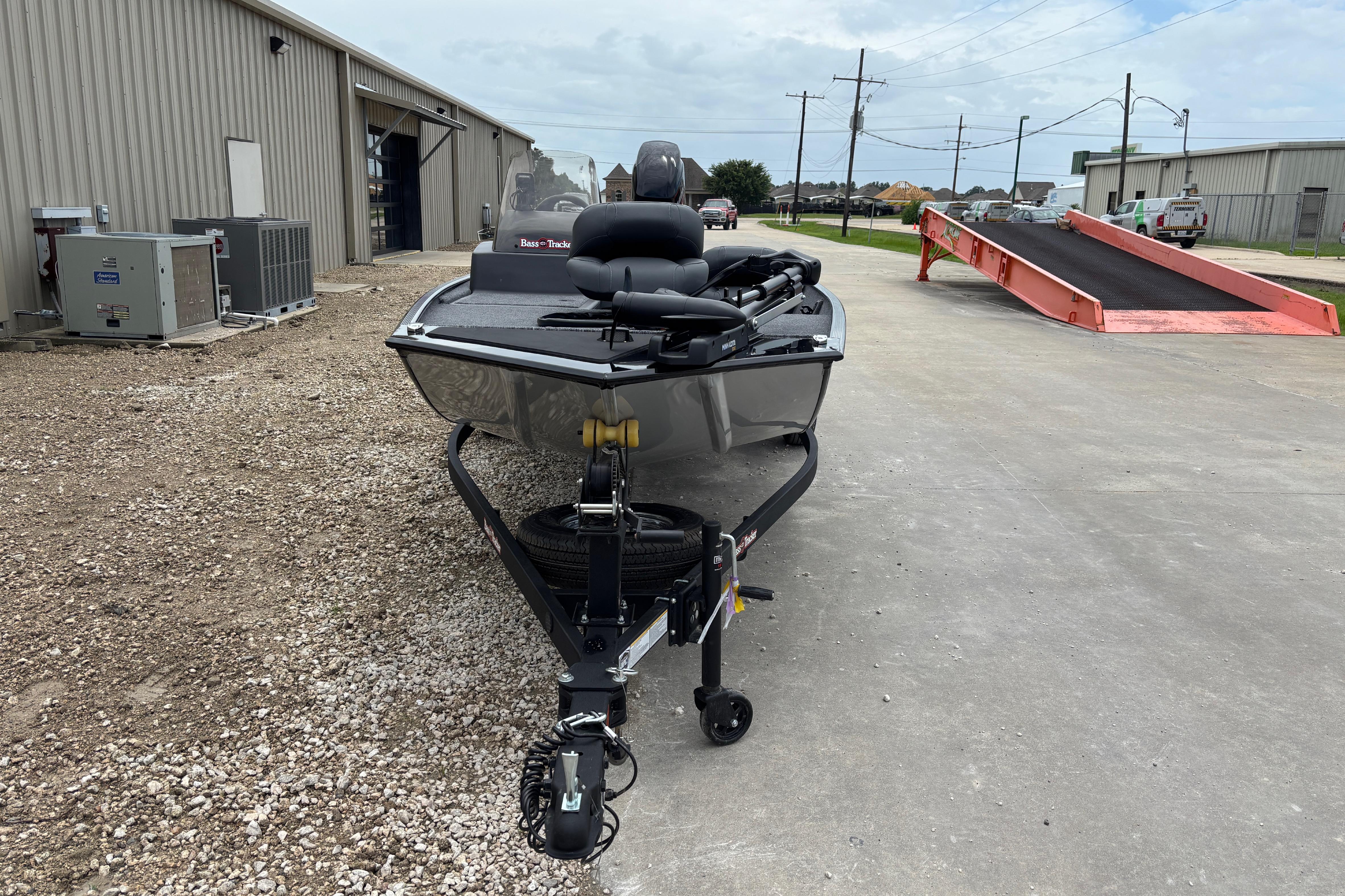 2026 Tracker Bass Tracker Classic XL boat on trailer, parked outside industrial building.