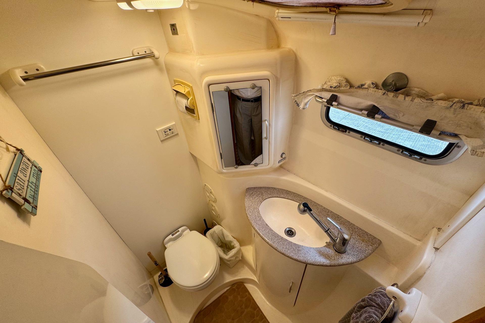 Compact bathroom in a 2004 Leopard 42 yacht with sink, toilet, and window.