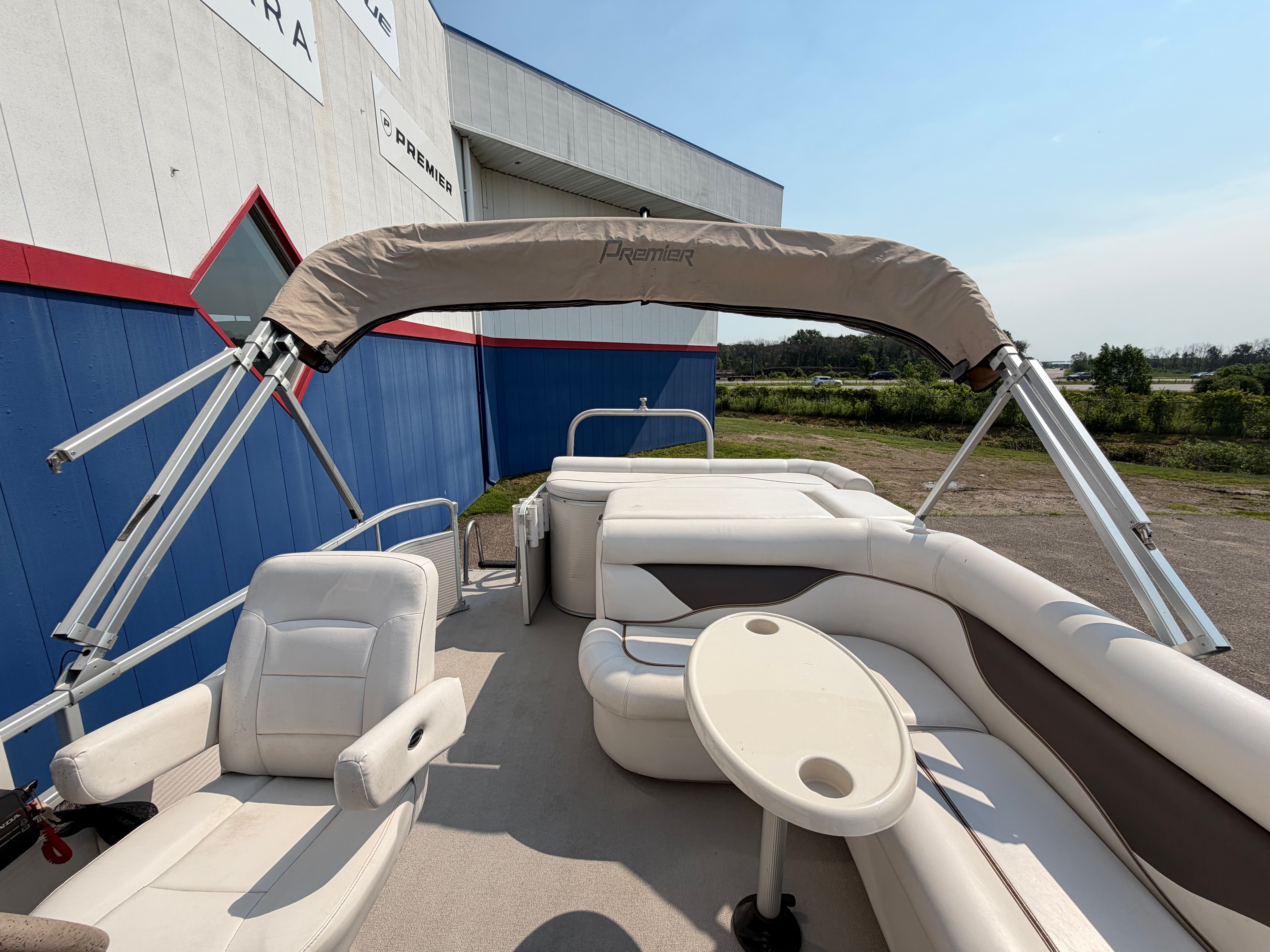 A 2007 Premier 225 Sunsation pontoon boat with beige seating and a Bimini top.