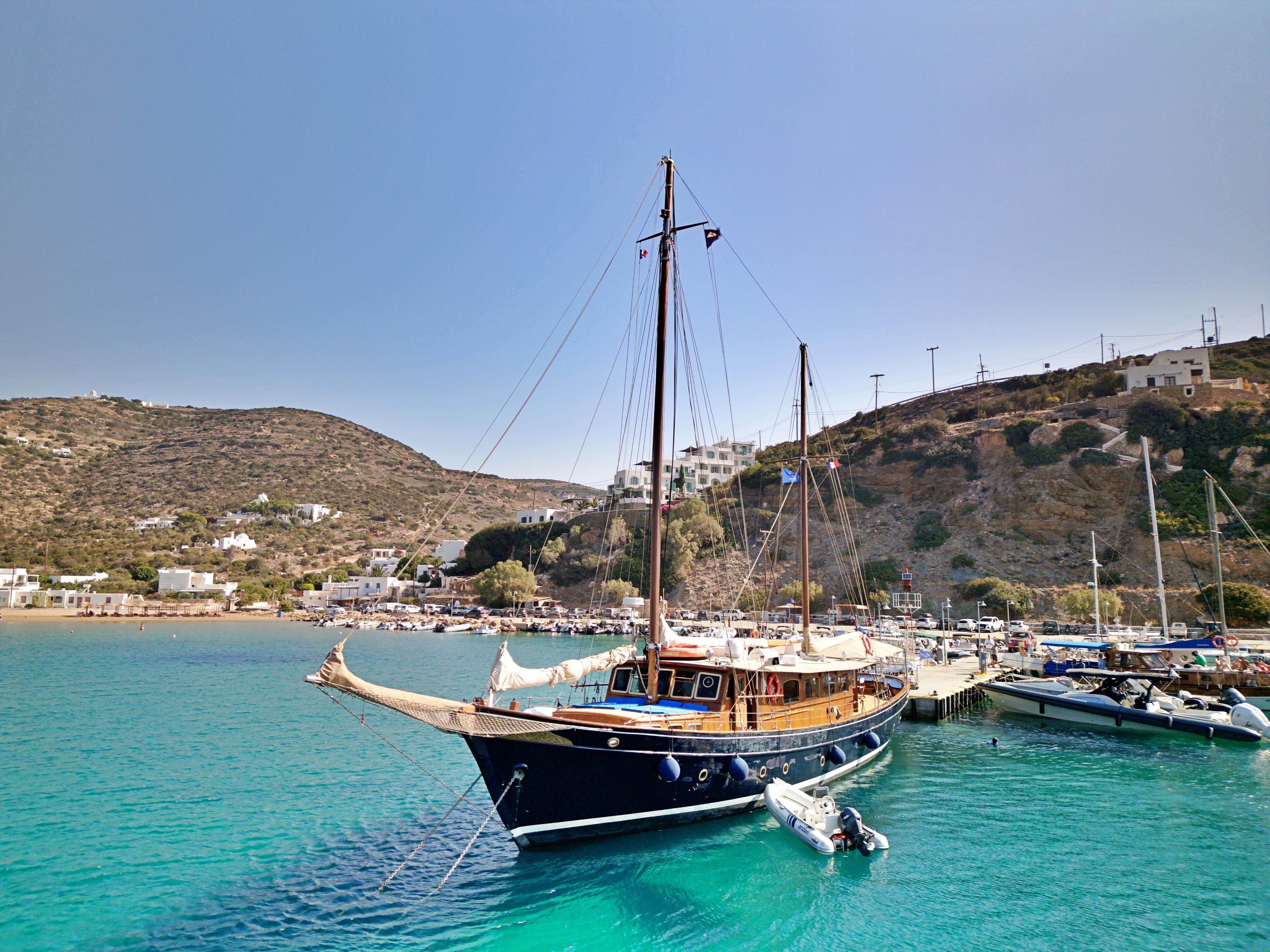Vintage 1969 Psarros Shipyard boat docked in clear turquoise waters, scenic coastal backdrop.