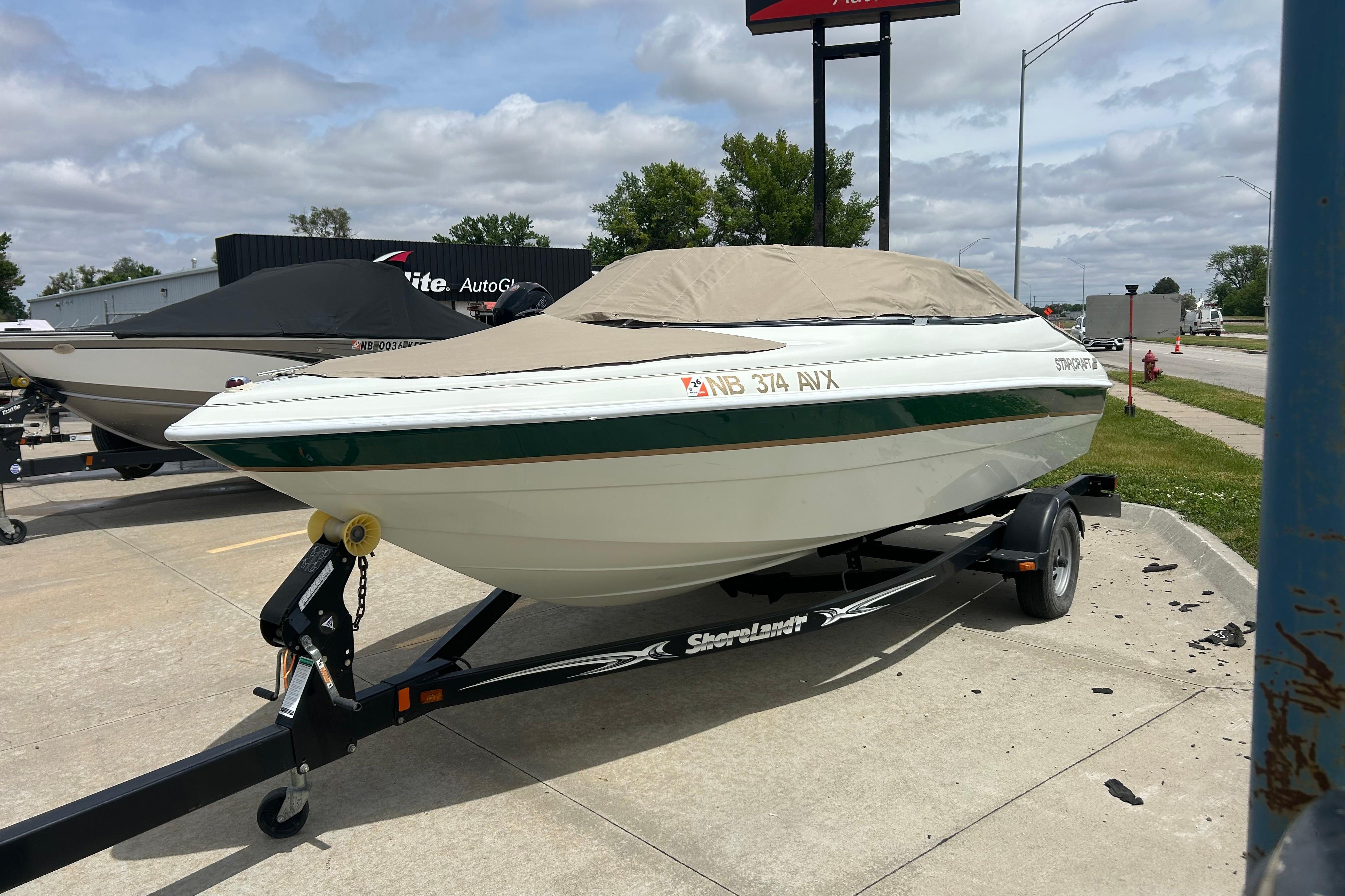 2000 Starcraft 1810 boat on trailer, covered, parked outdoors on a cloudy day.