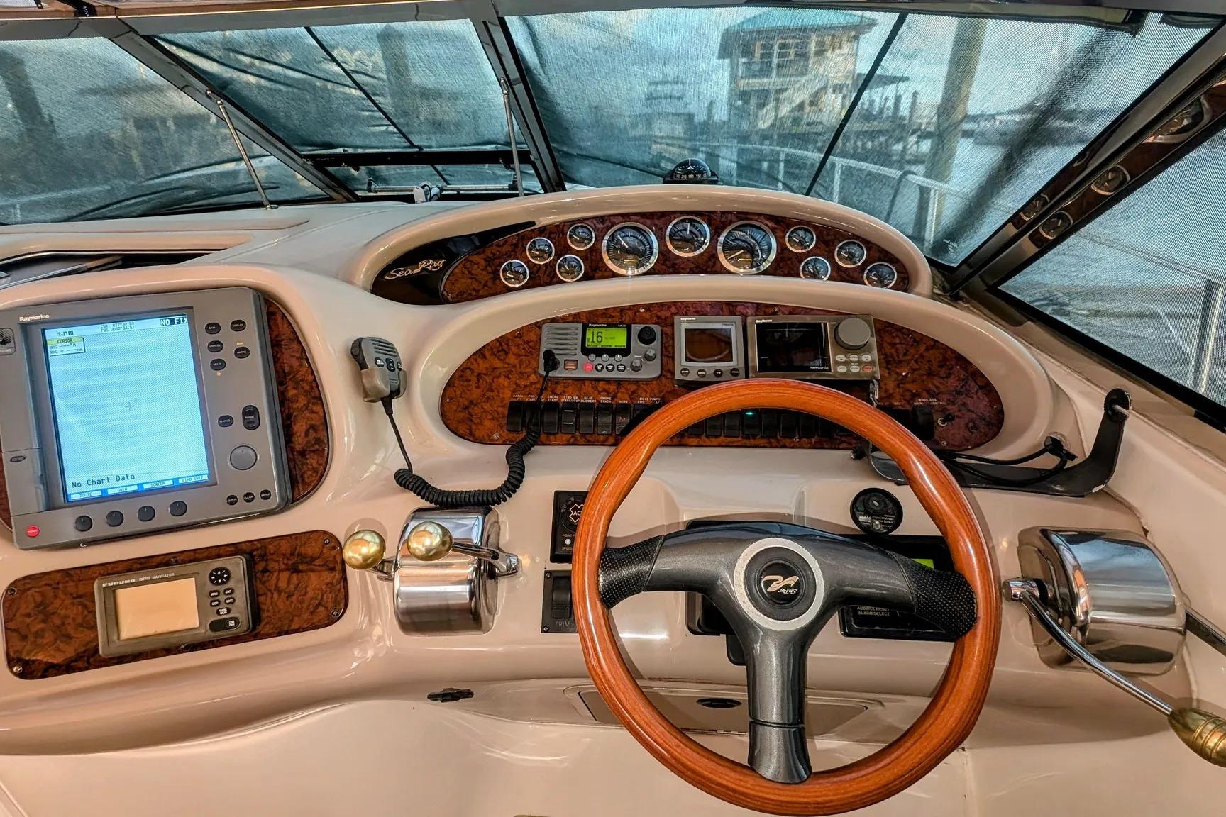 Cockpit of 2000 Sea Ray 380 Sundancer with navigation equipment and wooden steering wheel.