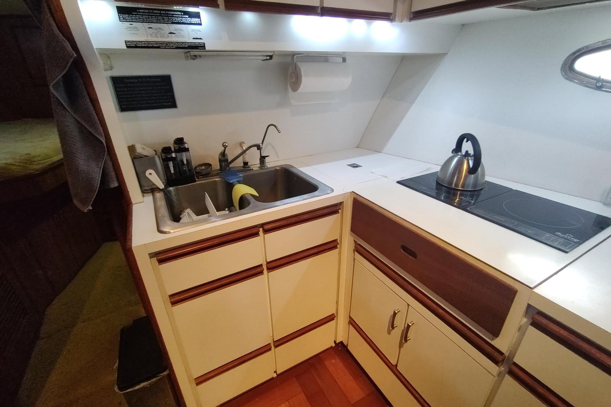 Compact kitchen in a 1989 Hyatt Double Cabin Motoryacht with sink and stovetop.