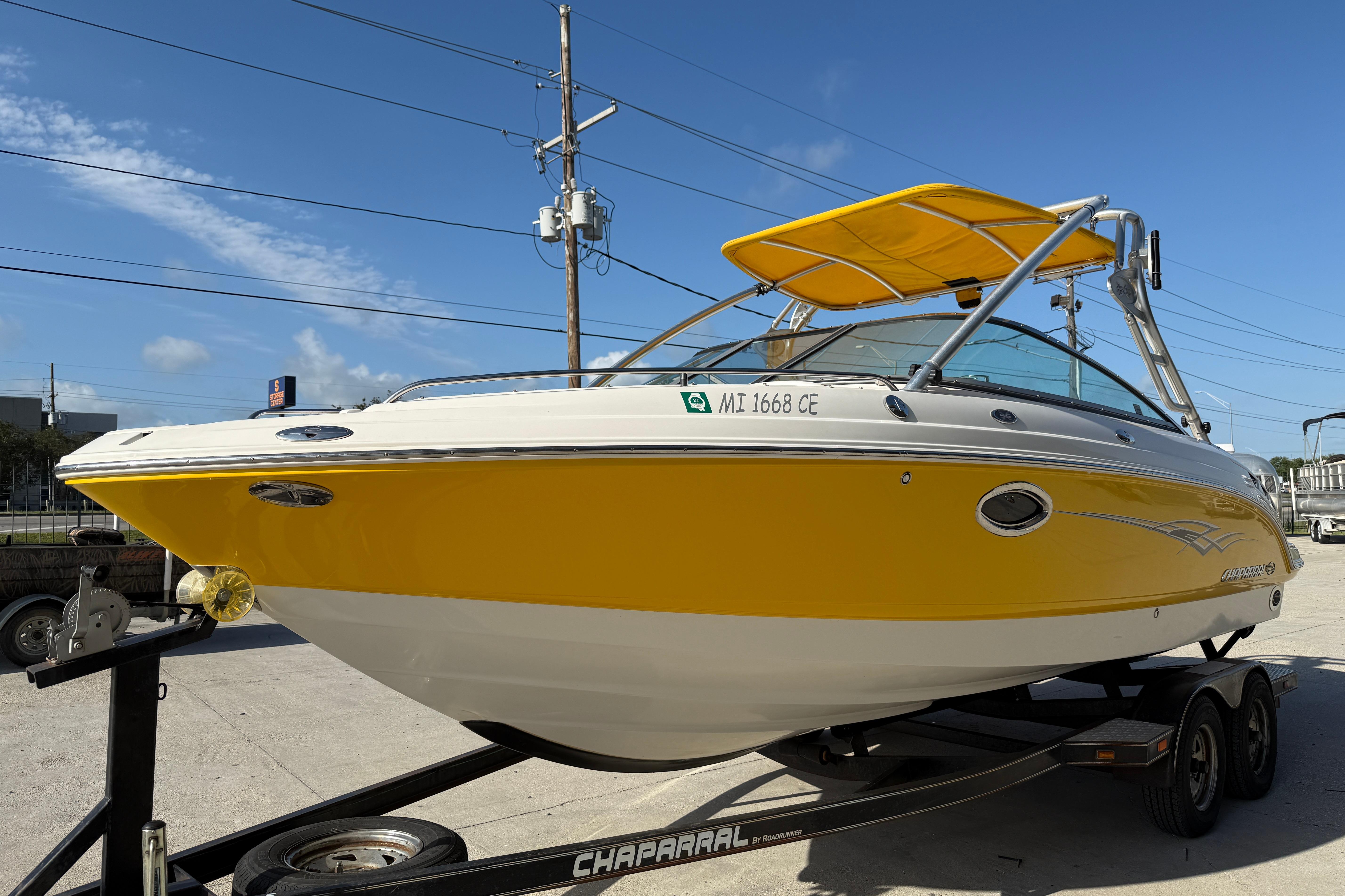 2008 Chaparral 236 SSX boat with yellow hull on trailer, sunny day background.