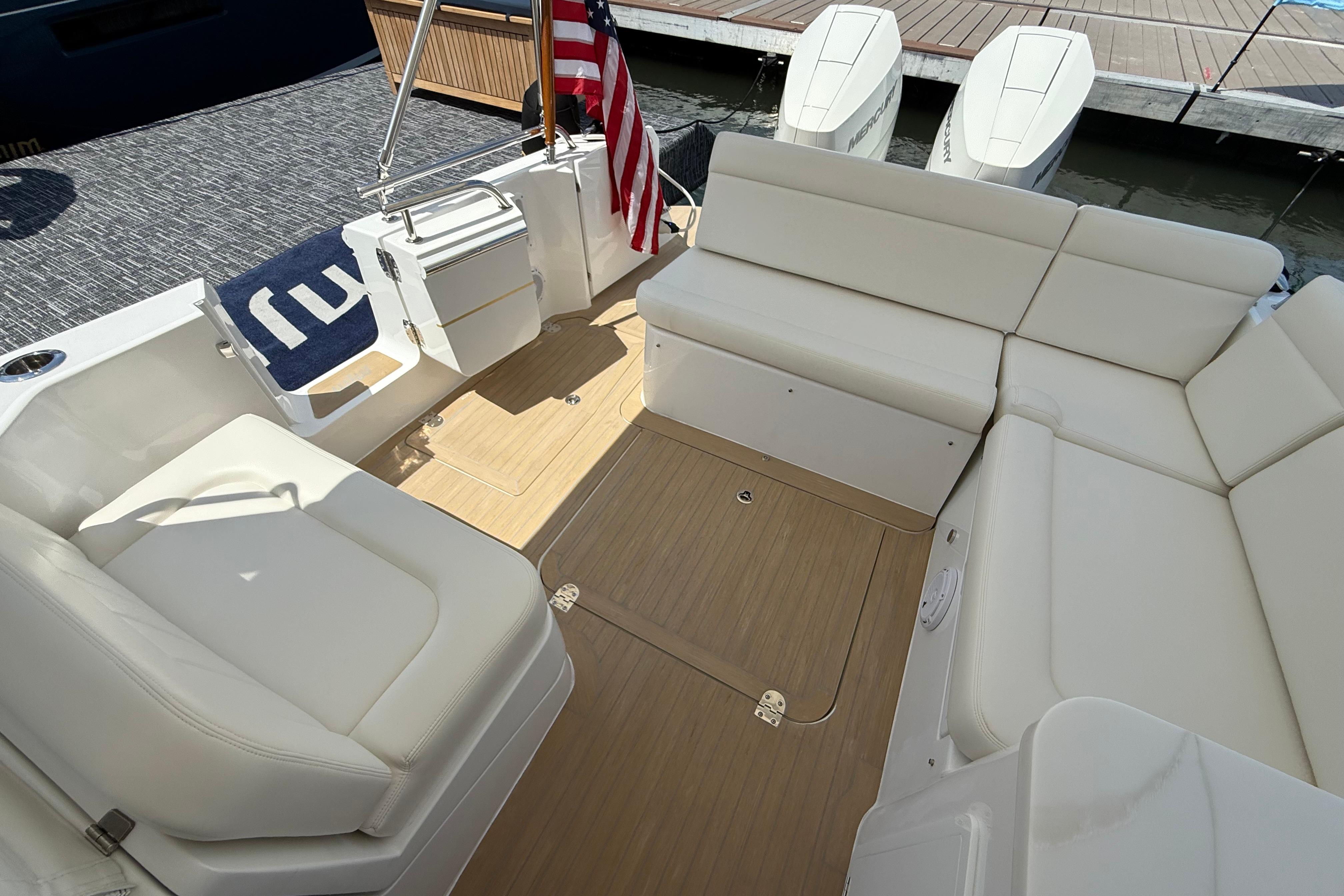 Luxurious seating area on 2026 MJM 38R yacht with American flag and outboard motors.