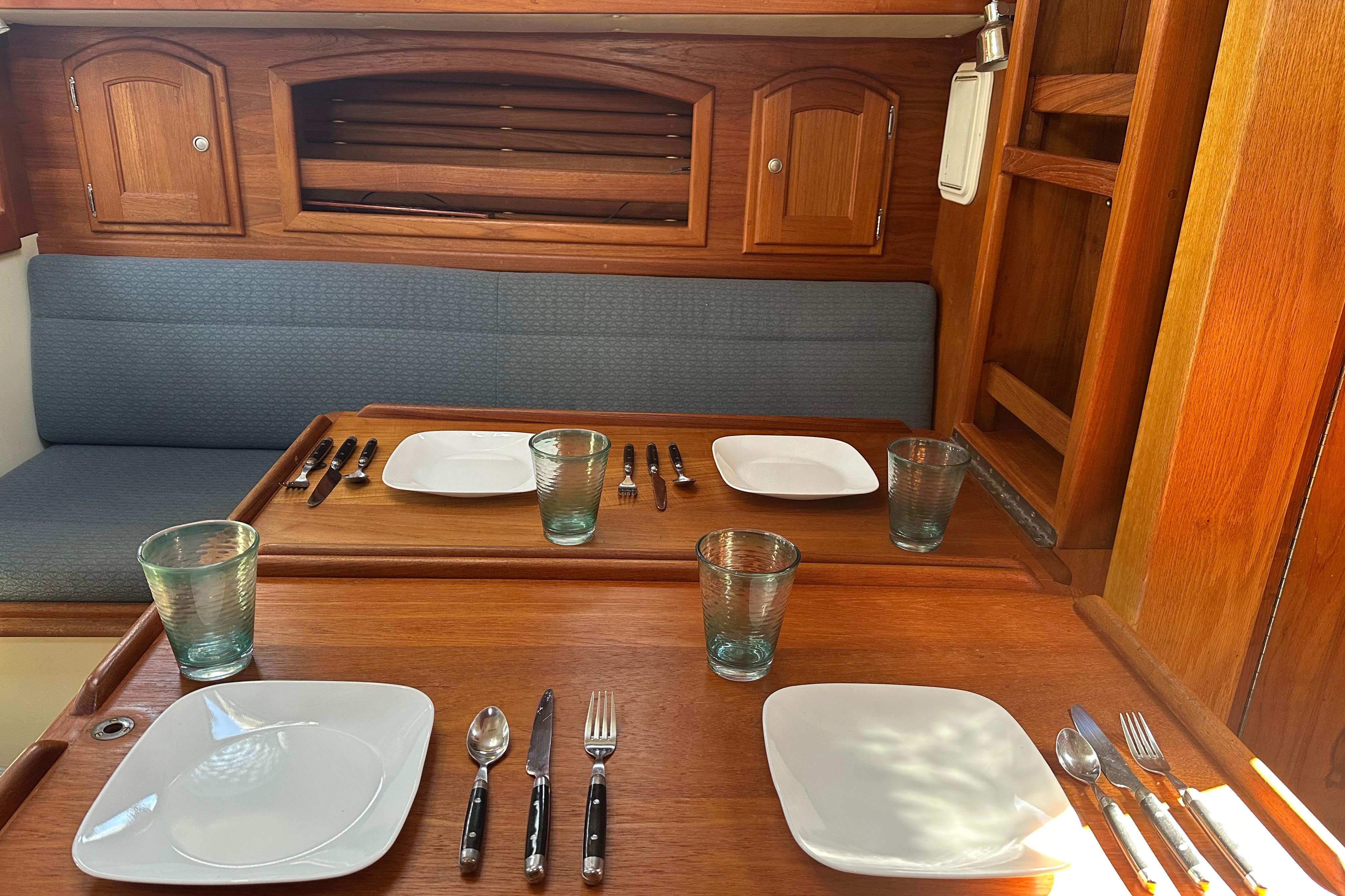 Dining area in 1997 Pacific Seacraft Crealock 34 sailboat with wooden interior and table setting.