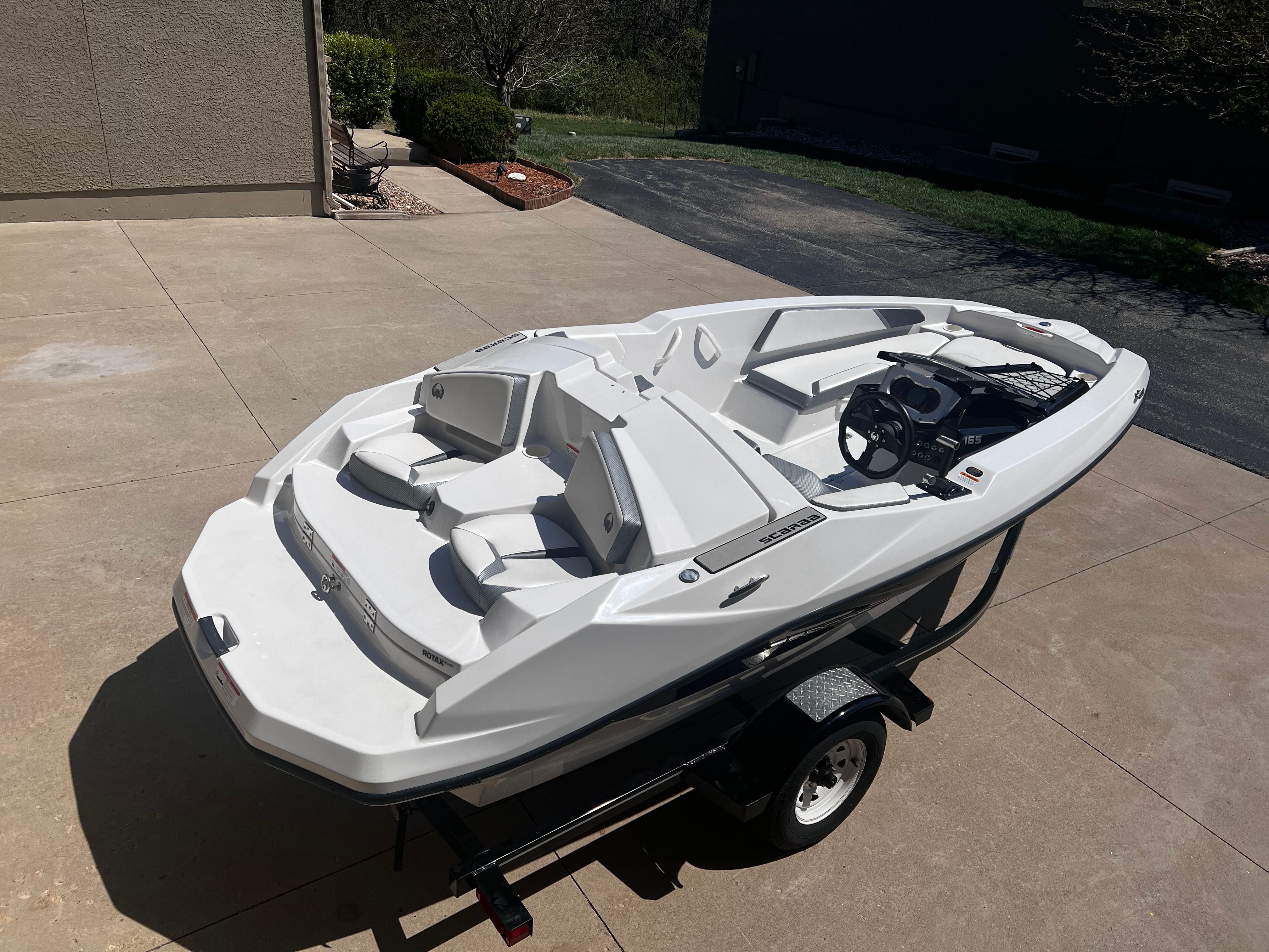 A white 2019 Scarab 165 G boat is on a trailer in a driveway.