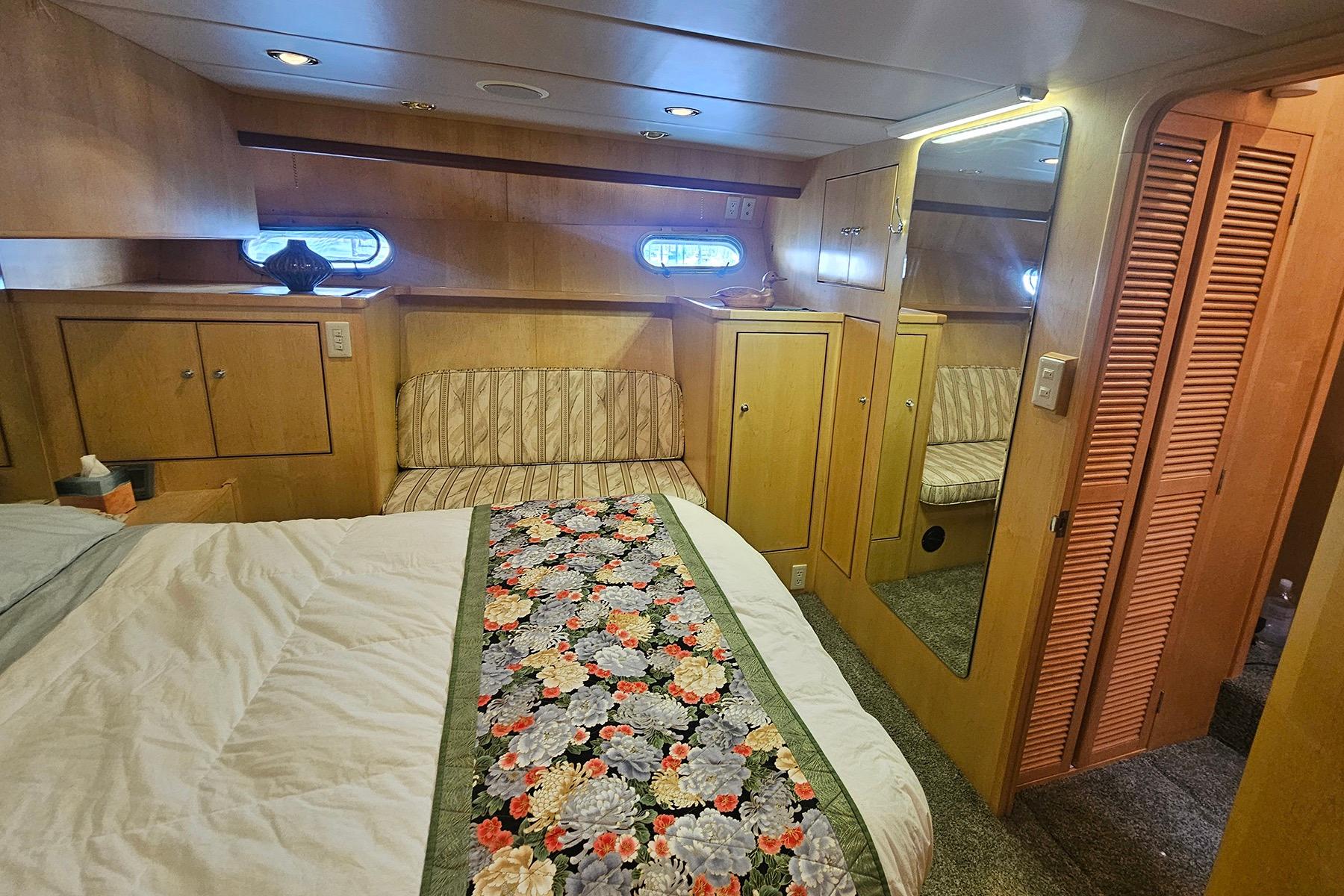 Luxurious 1995 Symbol 55 yacht bedroom with floral bedspread, wood paneling, and mirrored closet.
