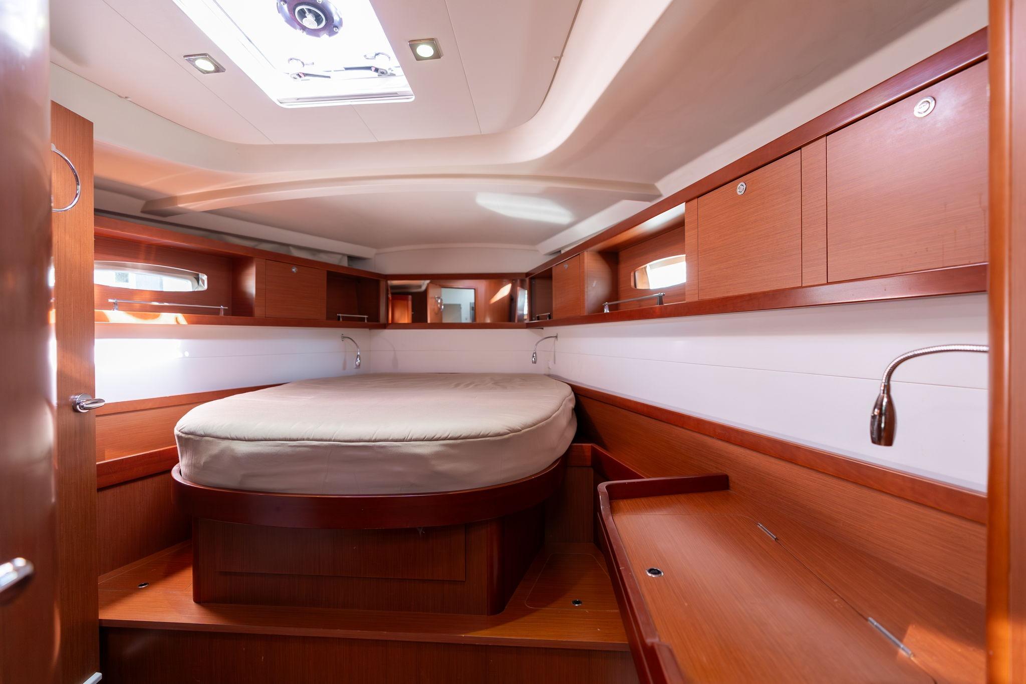 Interior cabin of 2013 Beneteau Oceanis 50 yacht, featuring wood finish and cozy bed.