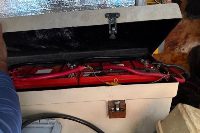 Battery compartment of a 1982 Lancer 45 Motorsailer with red cables and secure latch.