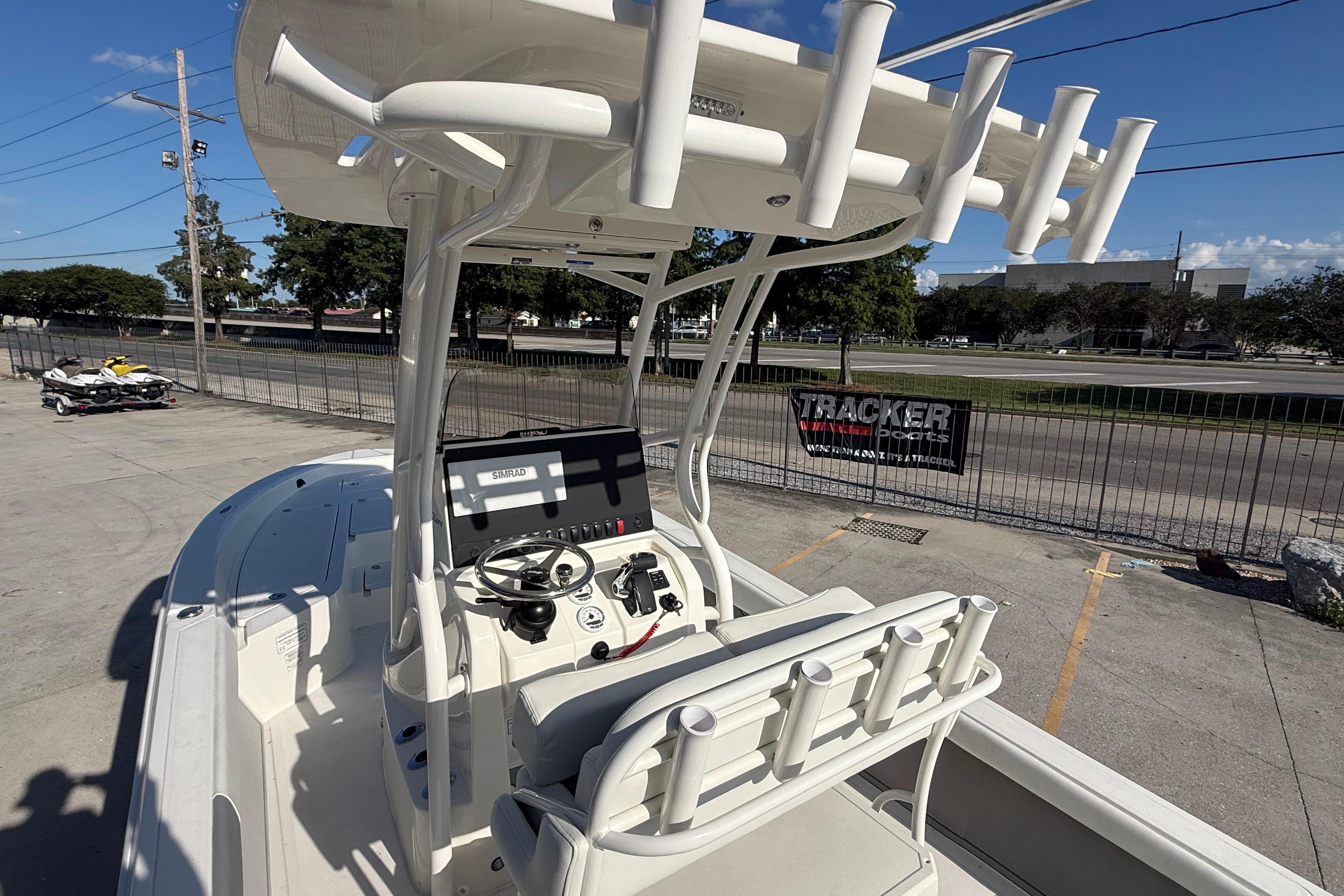 2026 Mako 24 APEX boat with advanced navigation system and rod holders, parked outdoors.