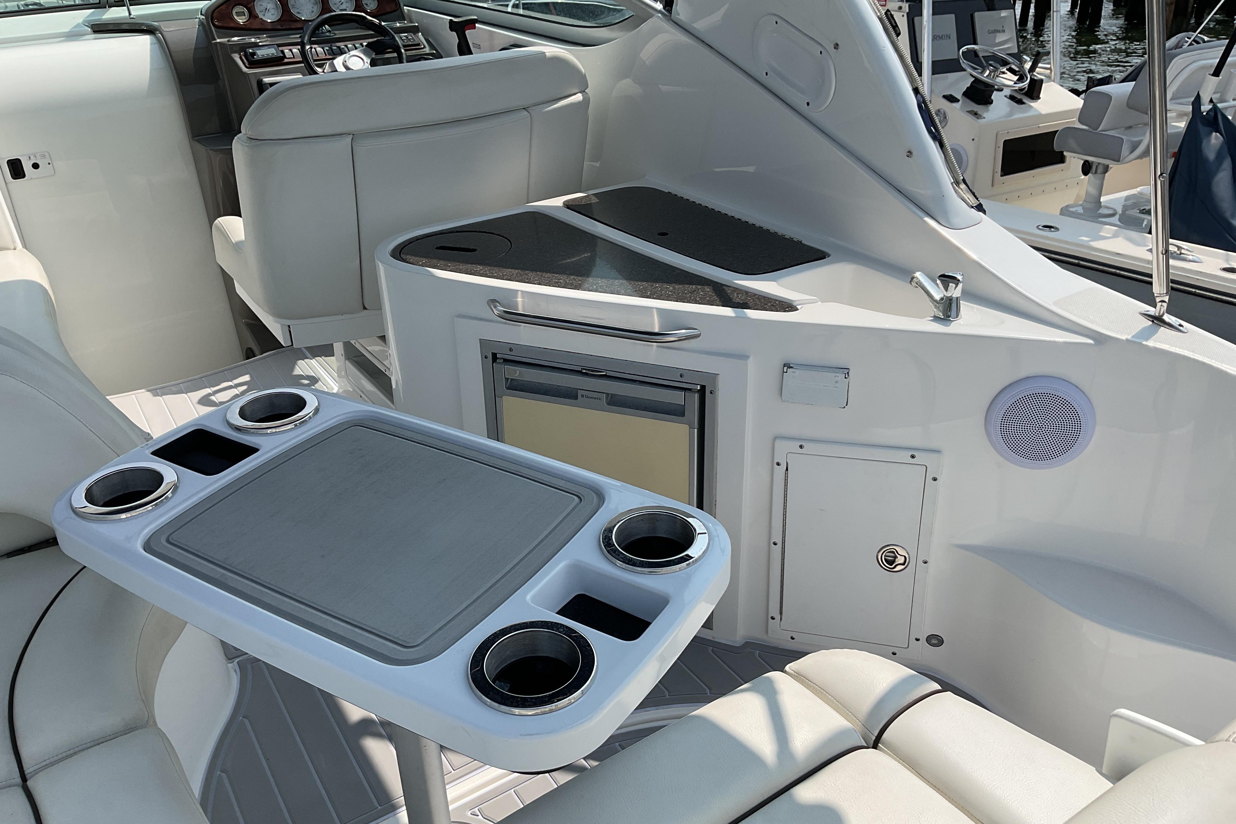 2013 Rinker 290 Express Cruiser interior with seating, table, and kitchenette area.