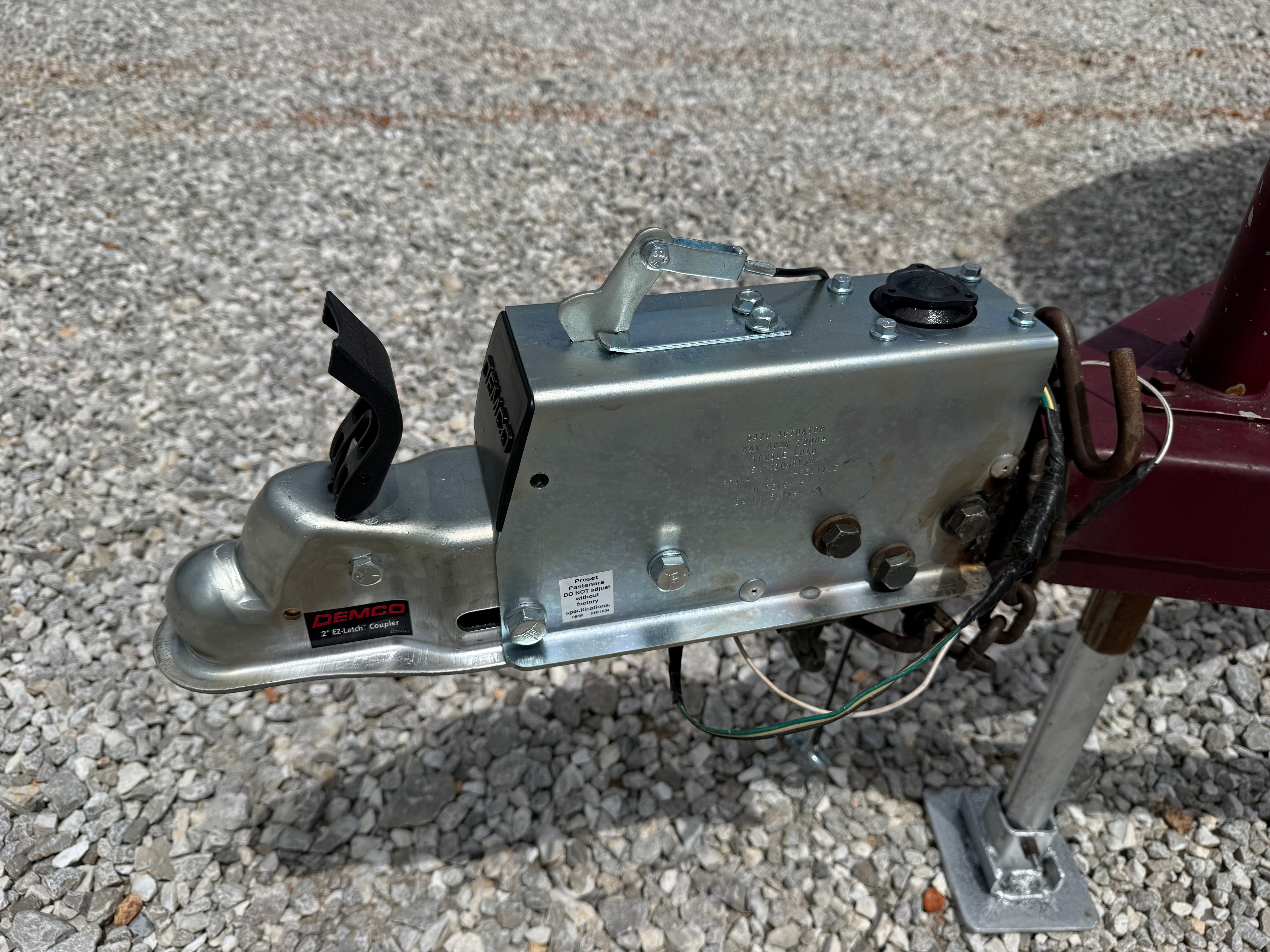Close-up of a trailer hitch on a gravel surface.