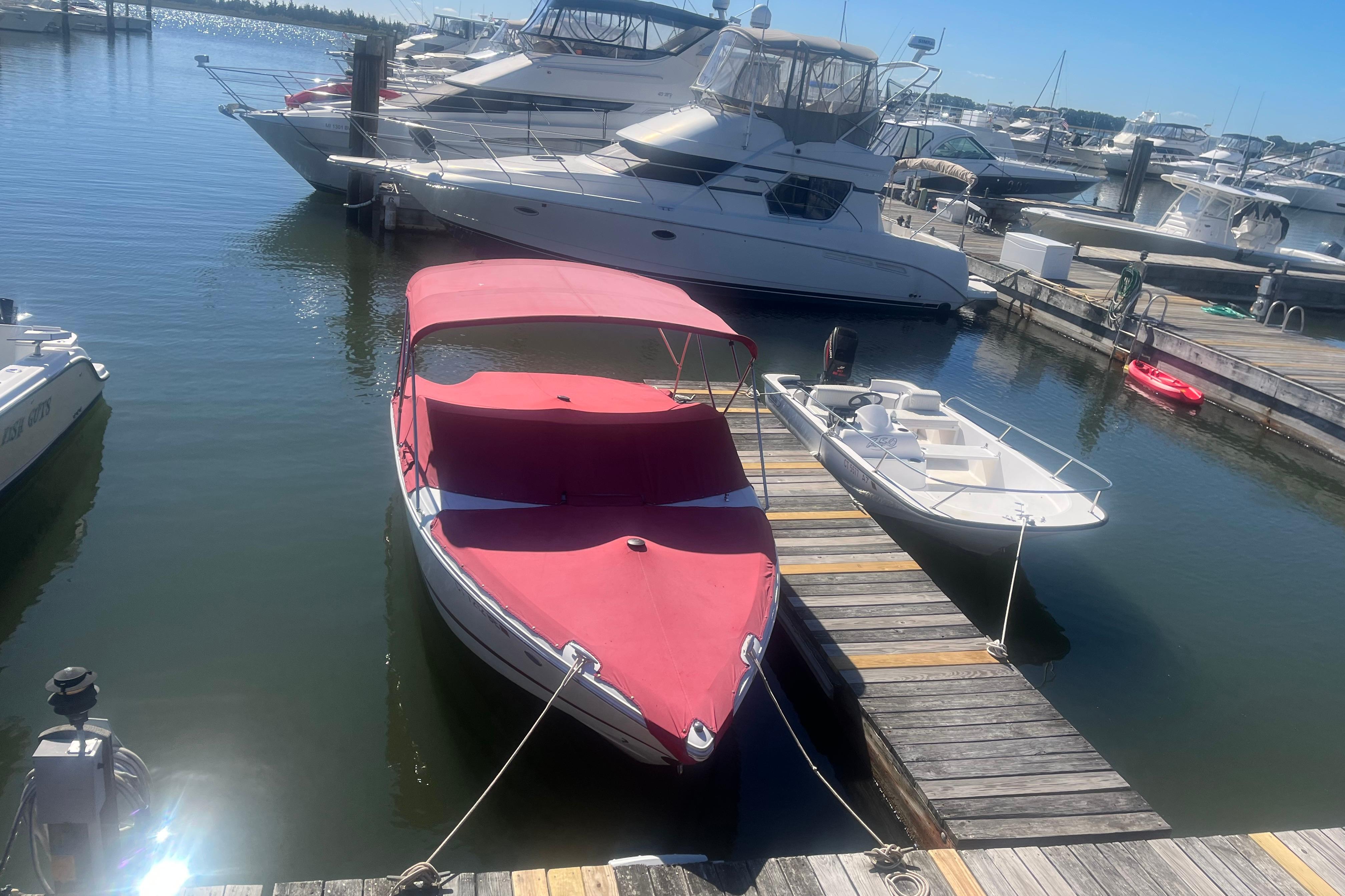 2011 Cobalt 210 boat with red cover docked at marina, surrounded by other boats.