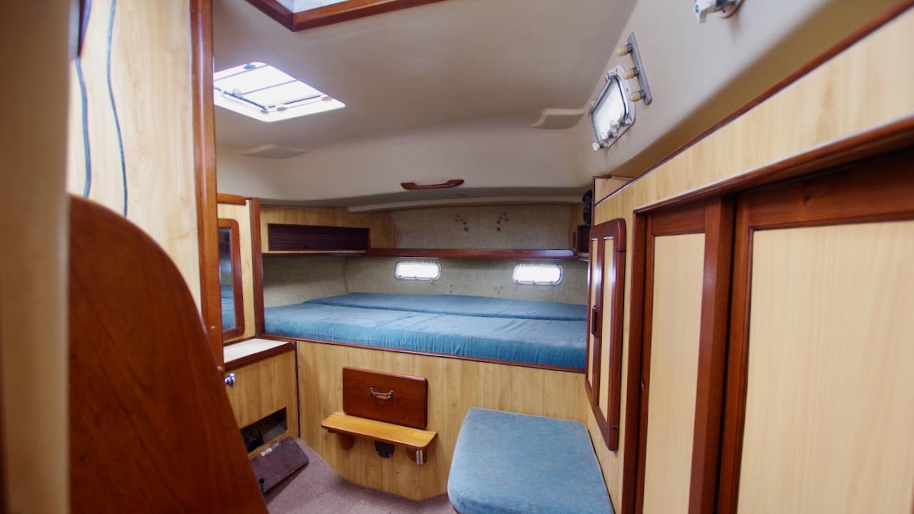 1981 Morgan Out Island 41 yacht cabin interior with wood paneling and blue bedding.