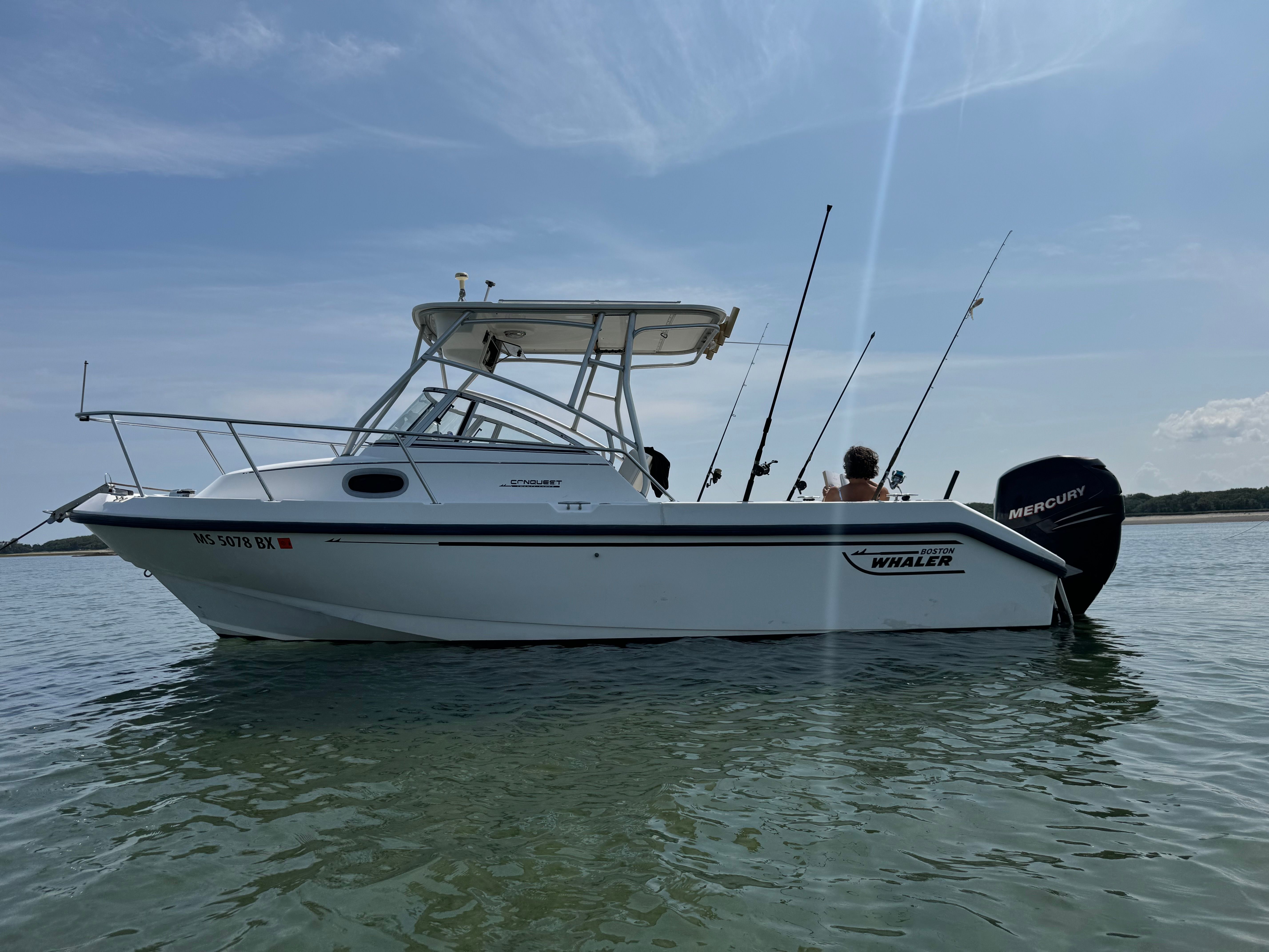 Boston Whaler Conquest 2000 on calm water with fishing rods.