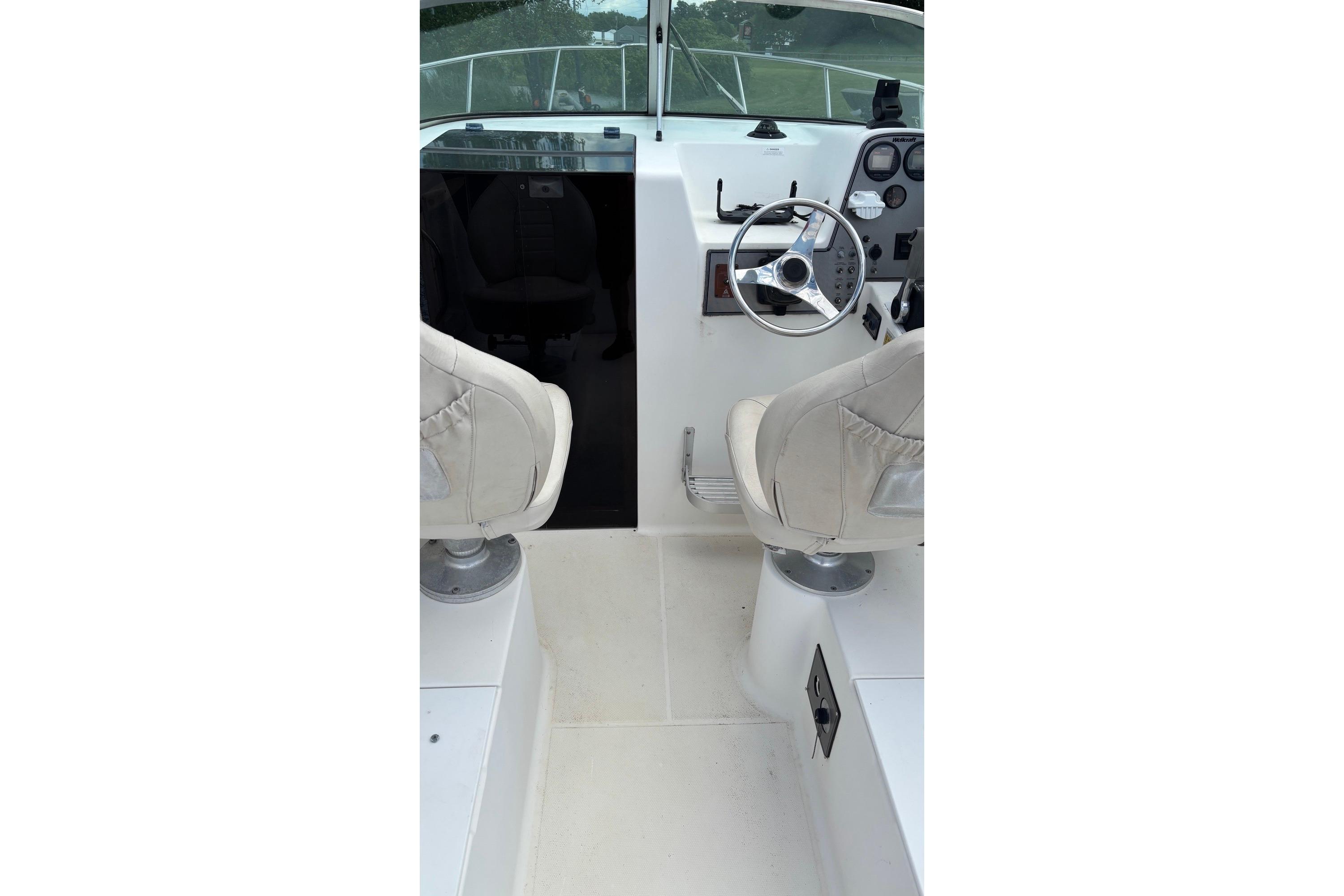 Interior view of 2002 Wellcraft 24 Walkaround boat cockpit with steering wheel and seats.