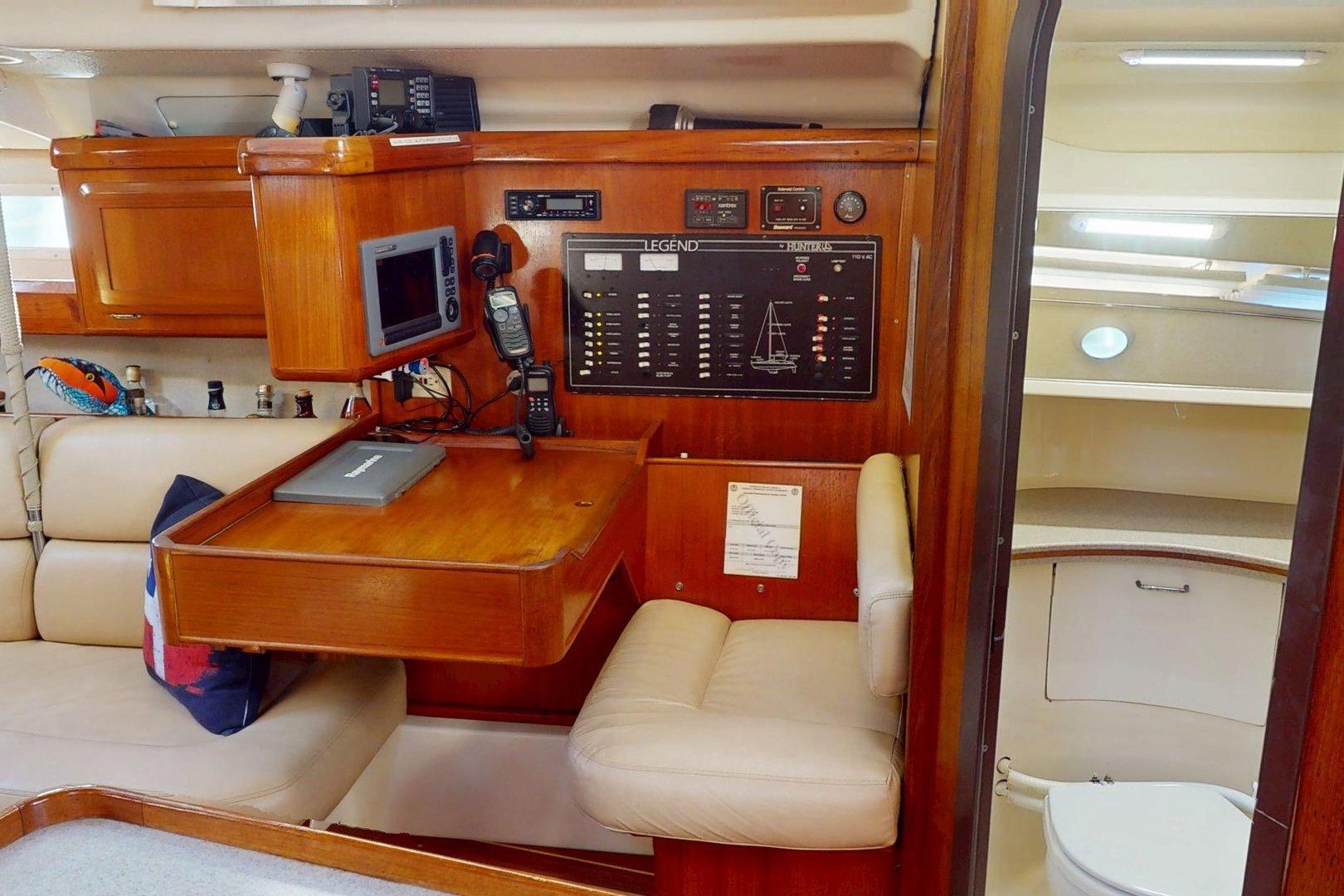 Interior of 1997 Hunter Legend 40.5 sailboat with navigation station and cozy seating area.