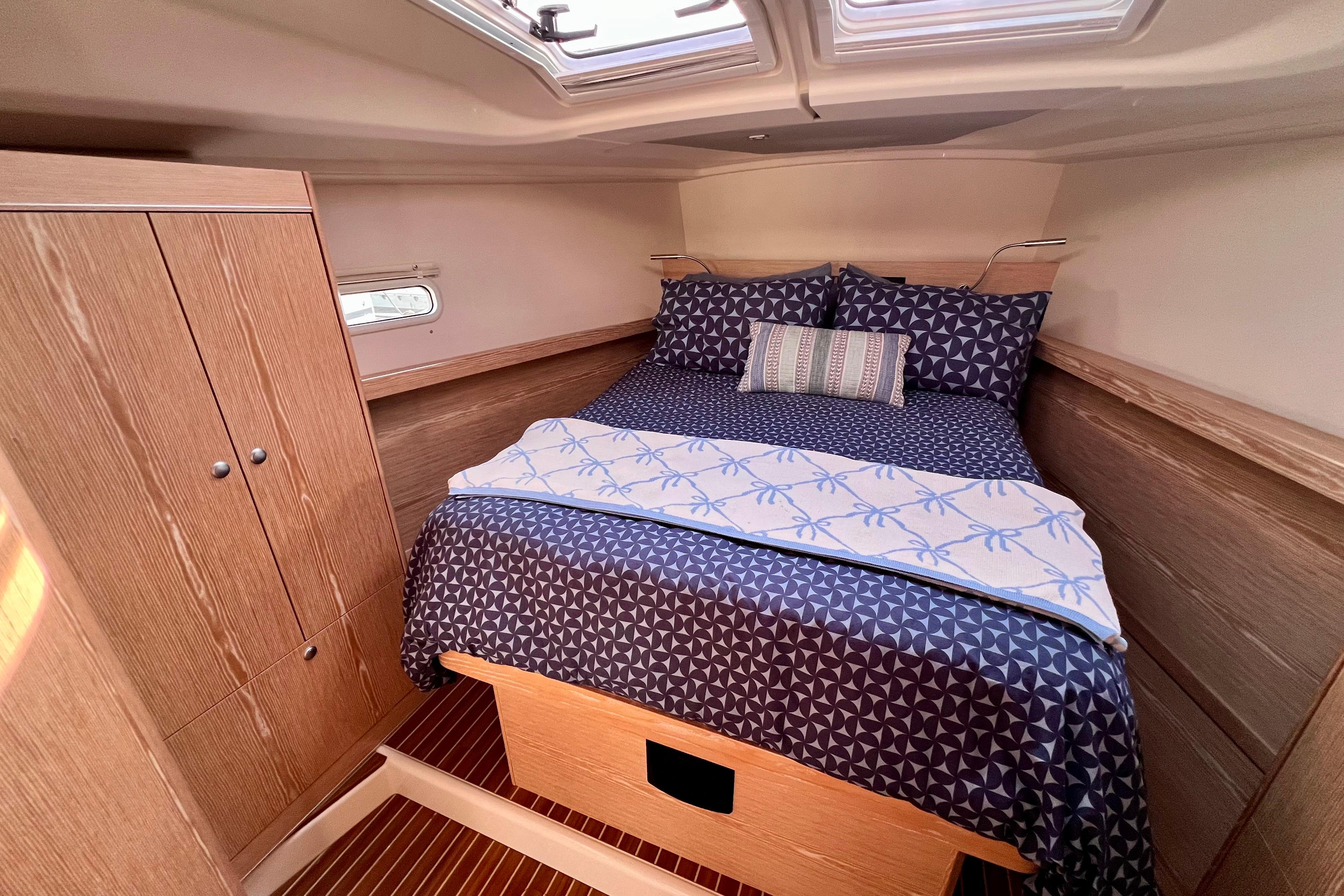 Cozy cabin interior of 2016 Hanse 455 yacht with stylish bedding and wooden cabinetry.