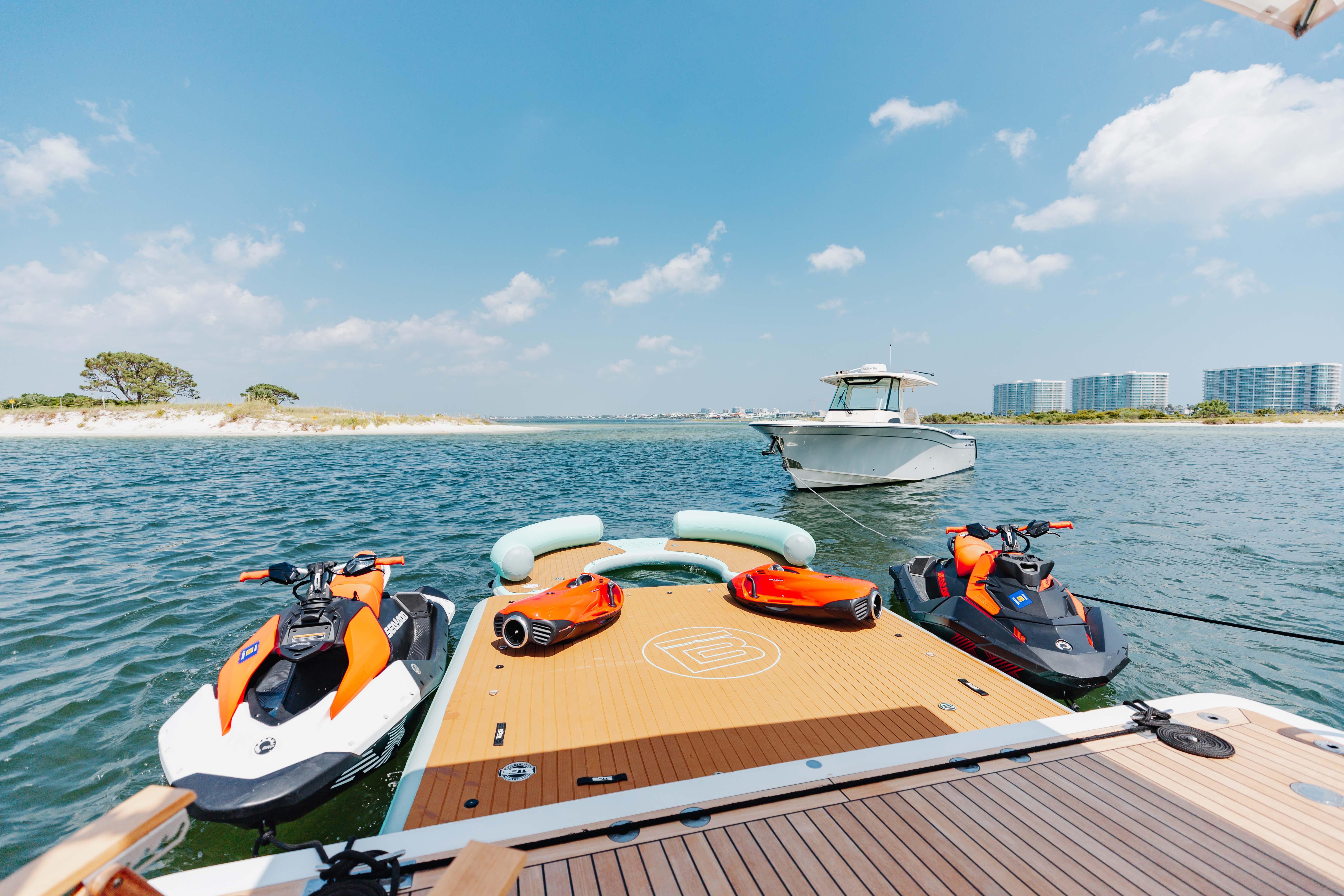 2019 Benetti Delfino 95 yacht with jet skis and scenic coastal view.