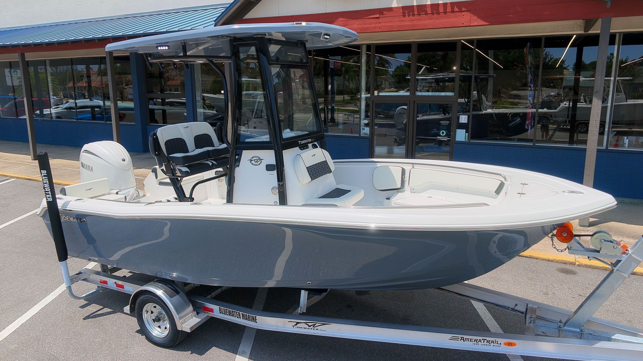 A gray Tidewater 198 CC Adventure boat from 2027 sits on a trailer in front of a building.