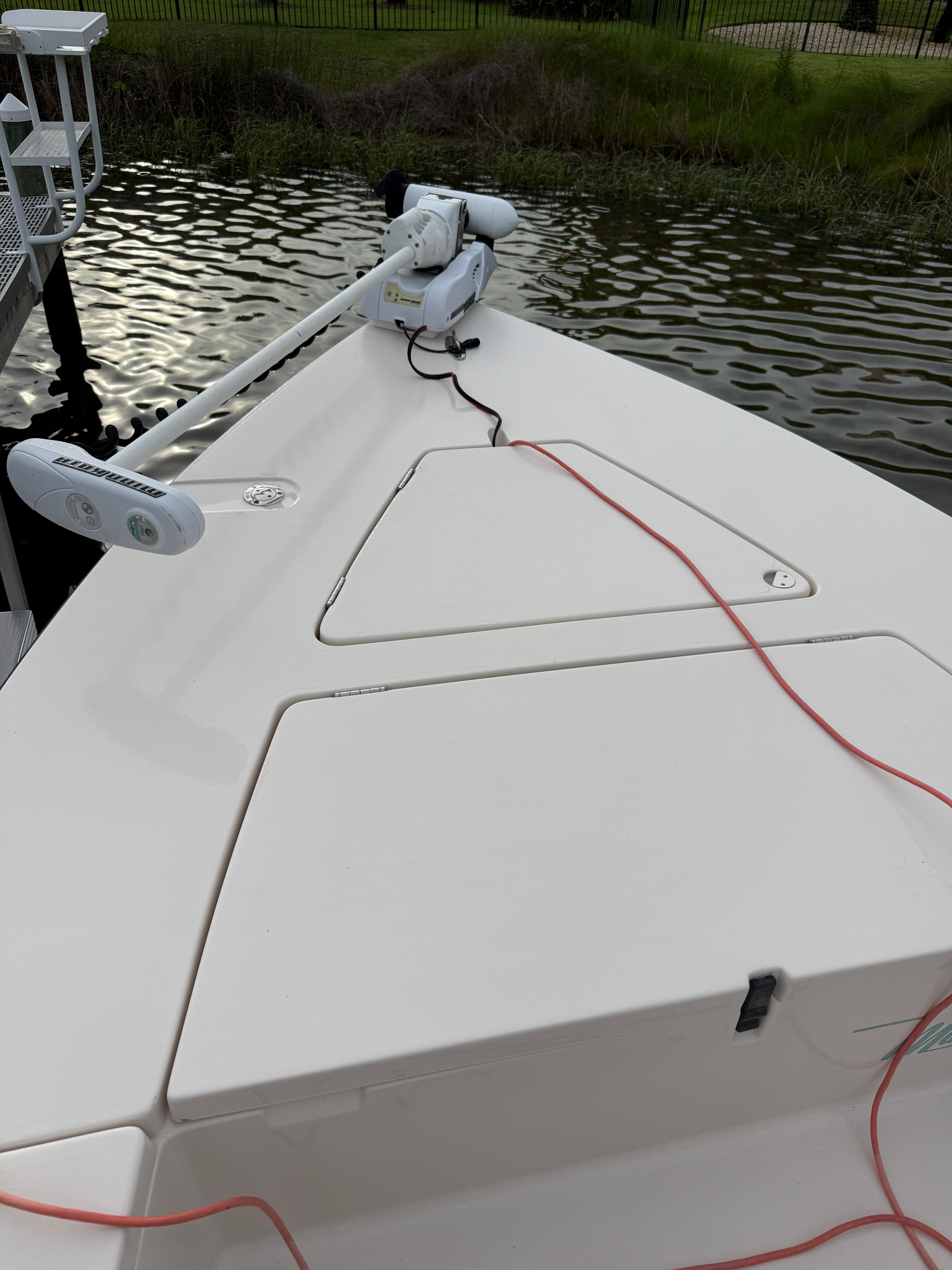 The boat features a clean, white deck with a trolling motor at the front.
