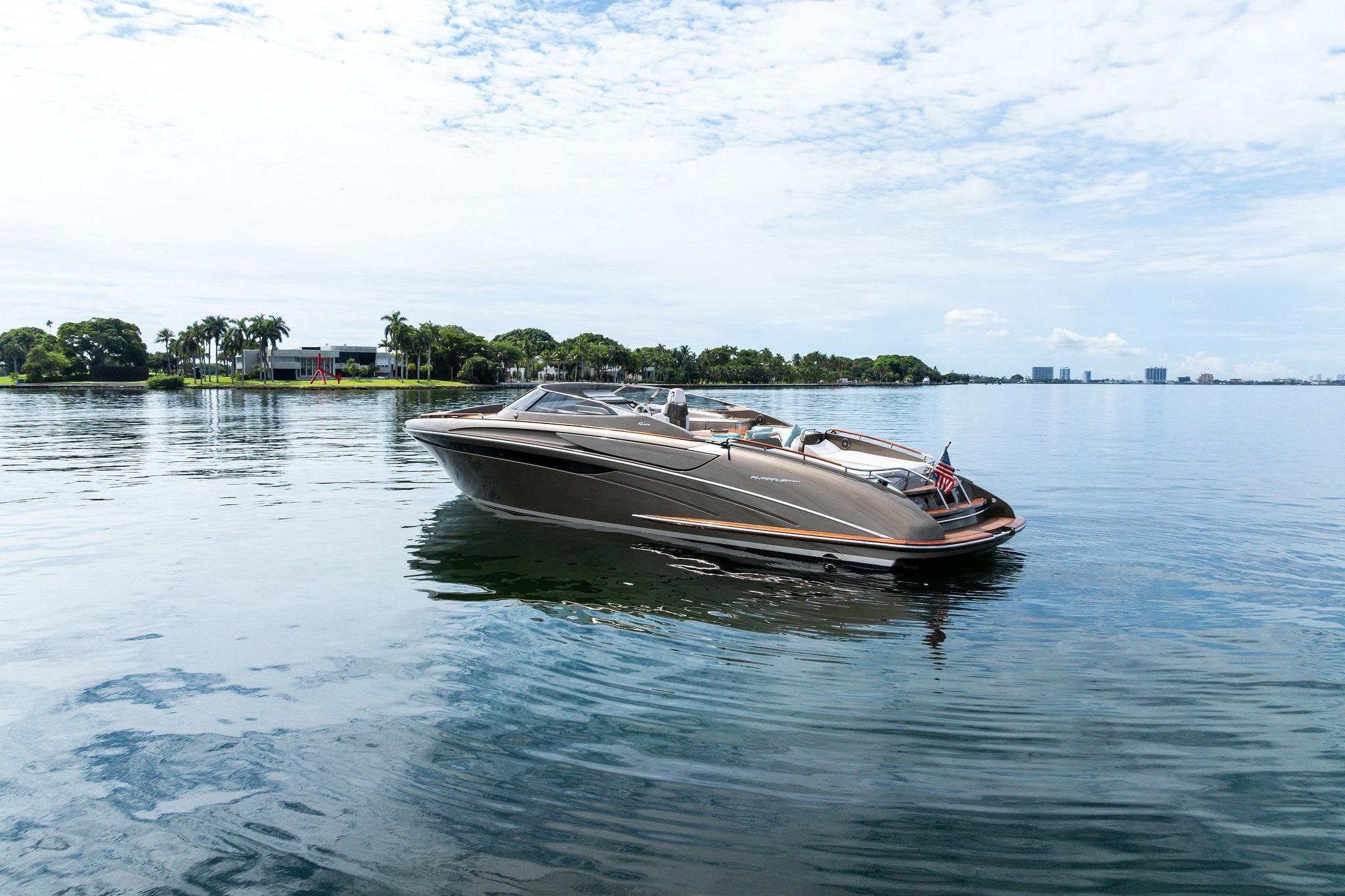 2014 Riva Rivarama luxury yacht on calm water, with scenic shoreline background.