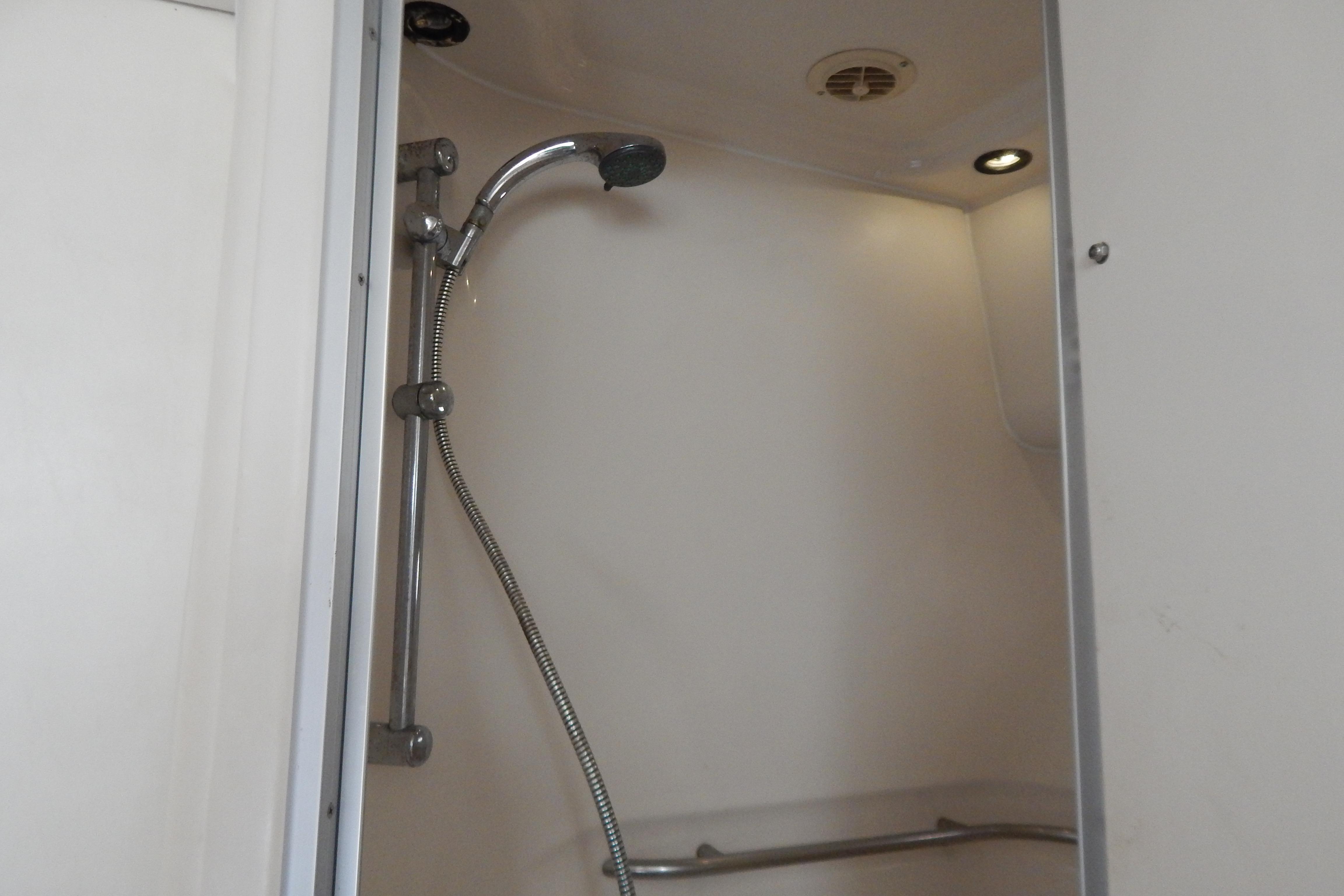 Shower area inside 1998 Magnum 4100 SCR, featuring a handheld showerhead and lighting.