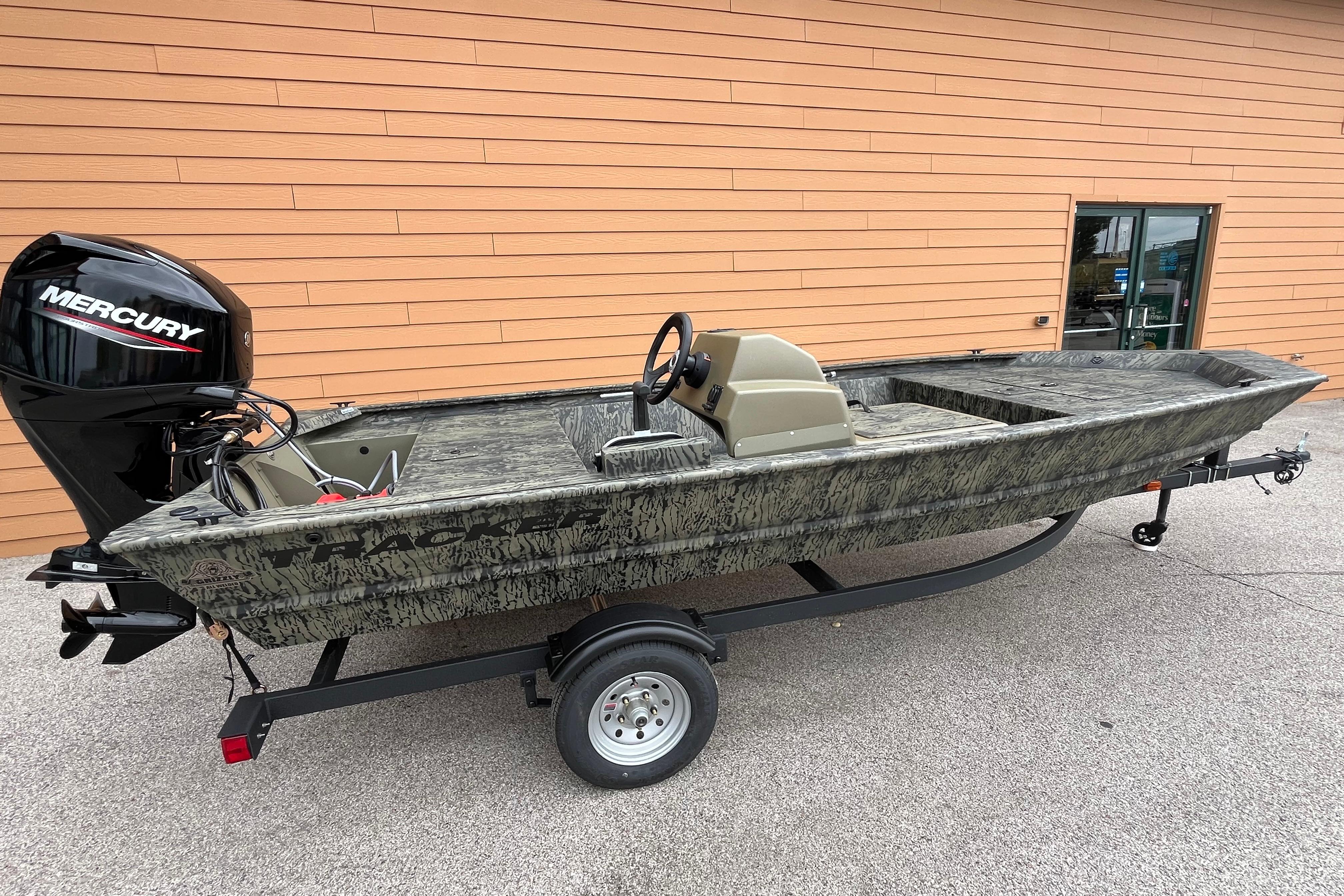 2026 Tracker Grizzly 1648 SC boat with Mercury engine on trailer, parked outdoors.