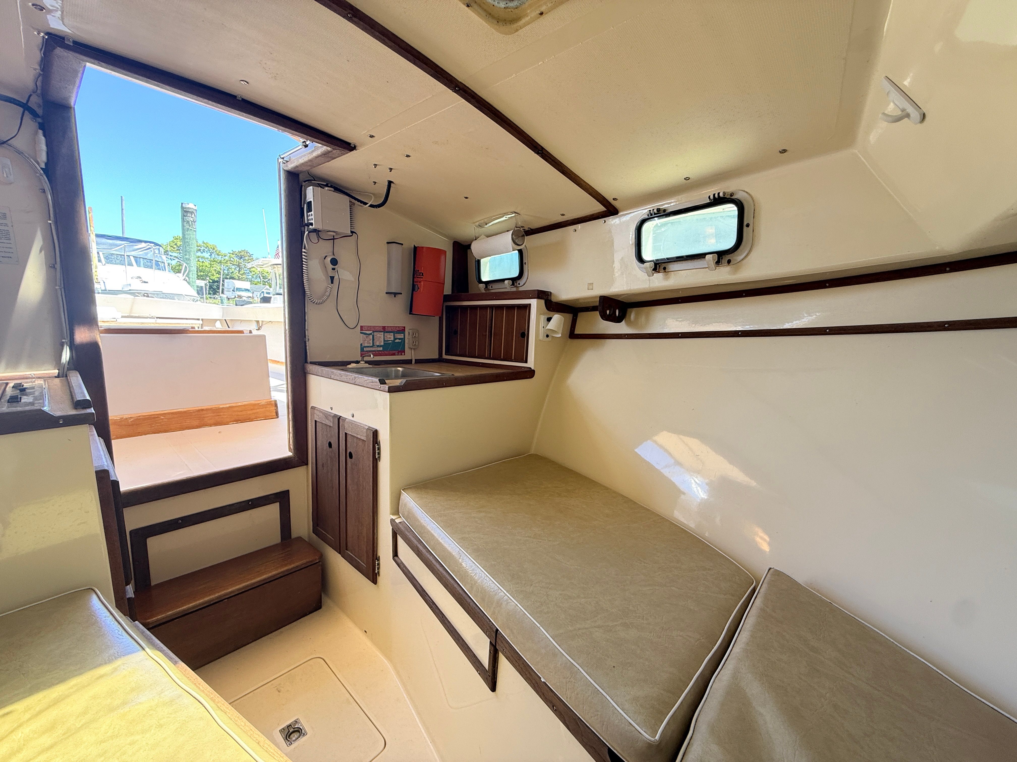 Interior of a 1989 Fortier 26 with seating area and windows.